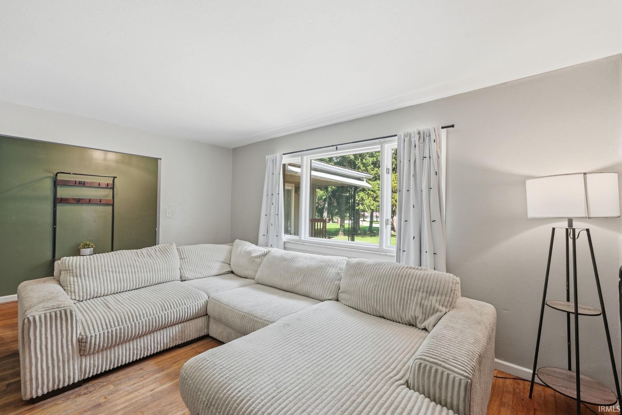 Spacious living area featuring wood-finish flooring, a large picture window, and neutral wall tones