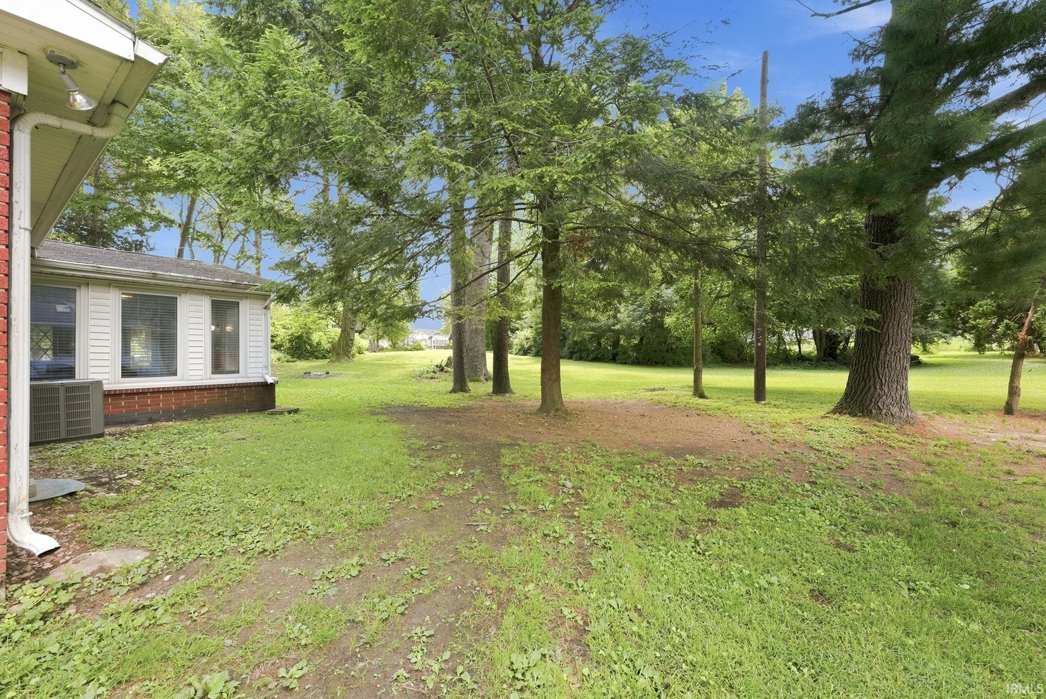 Expansive rear yard featuring mature trees and a substantial grassy area