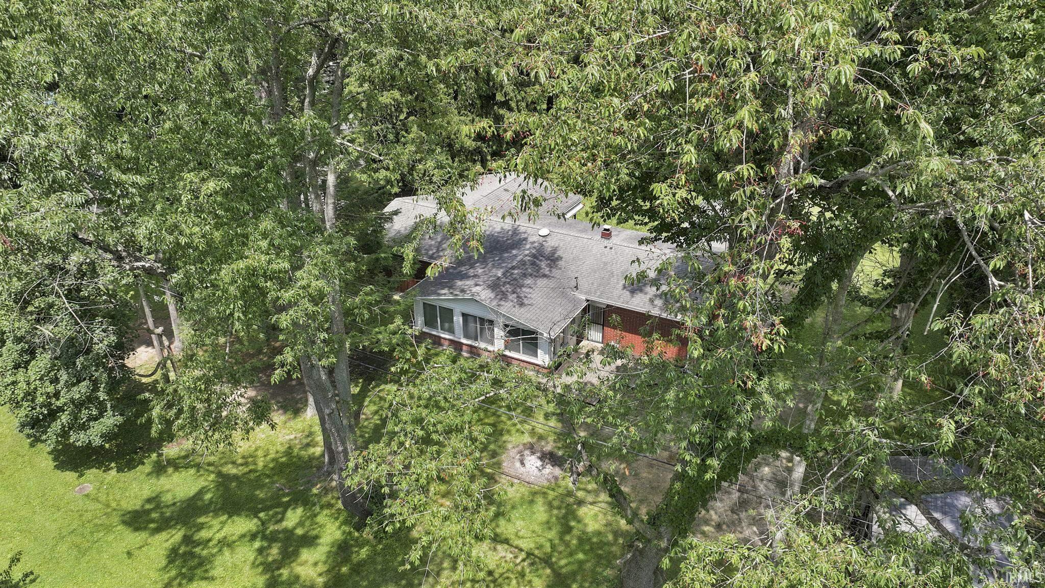 Property nestled among abundant mature trees, featuring a gabled roofline and red brick exterior