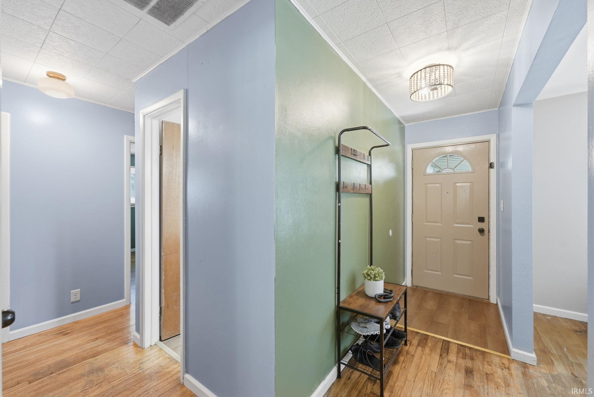 Entryway featuring wood-finish flooring, a neutral-toned door with an arched glass insert, and a contemporary ceiling light fixture
