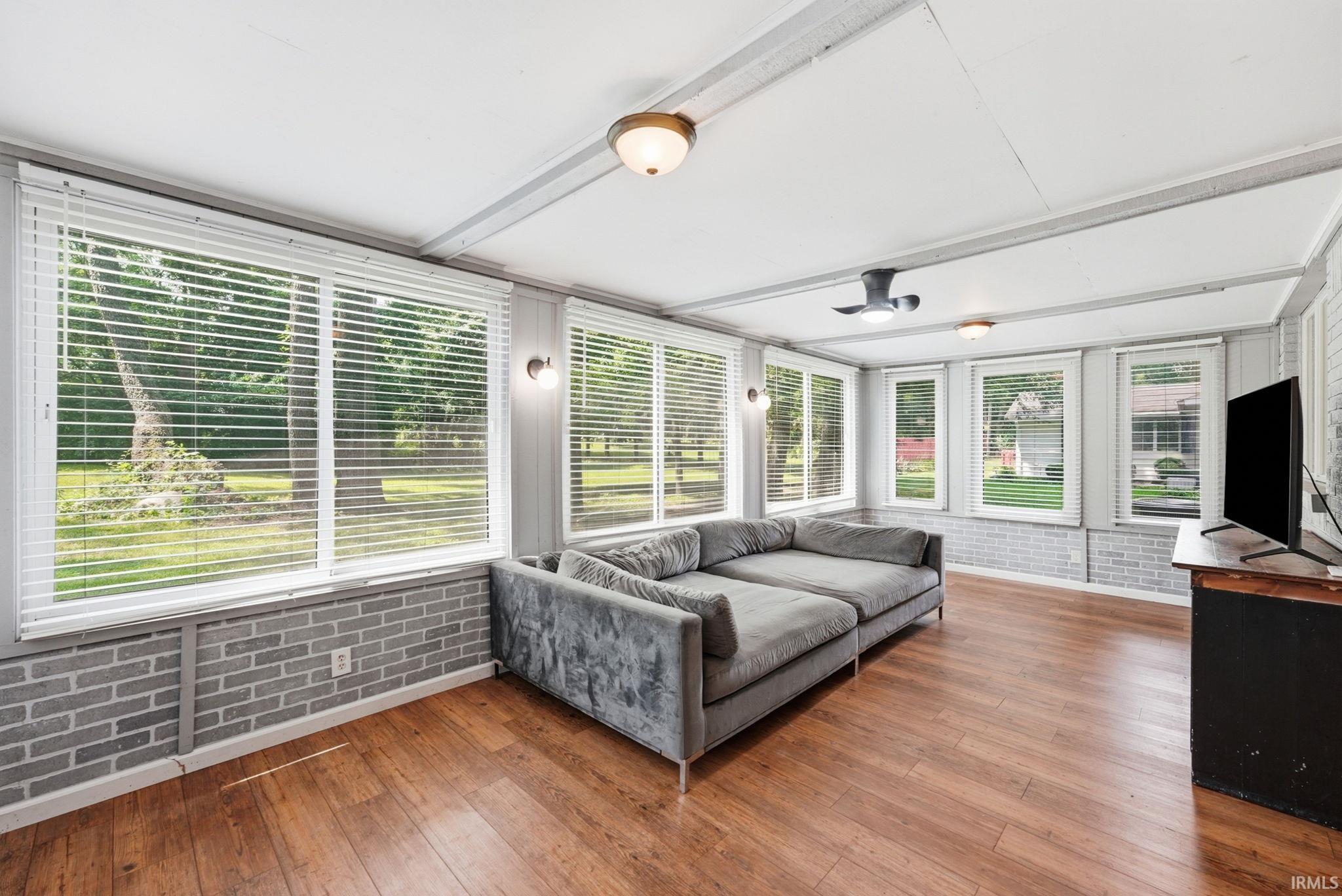 Room featuring abundant natural light, wood-finish flooring, and painted brick-style wainscoting