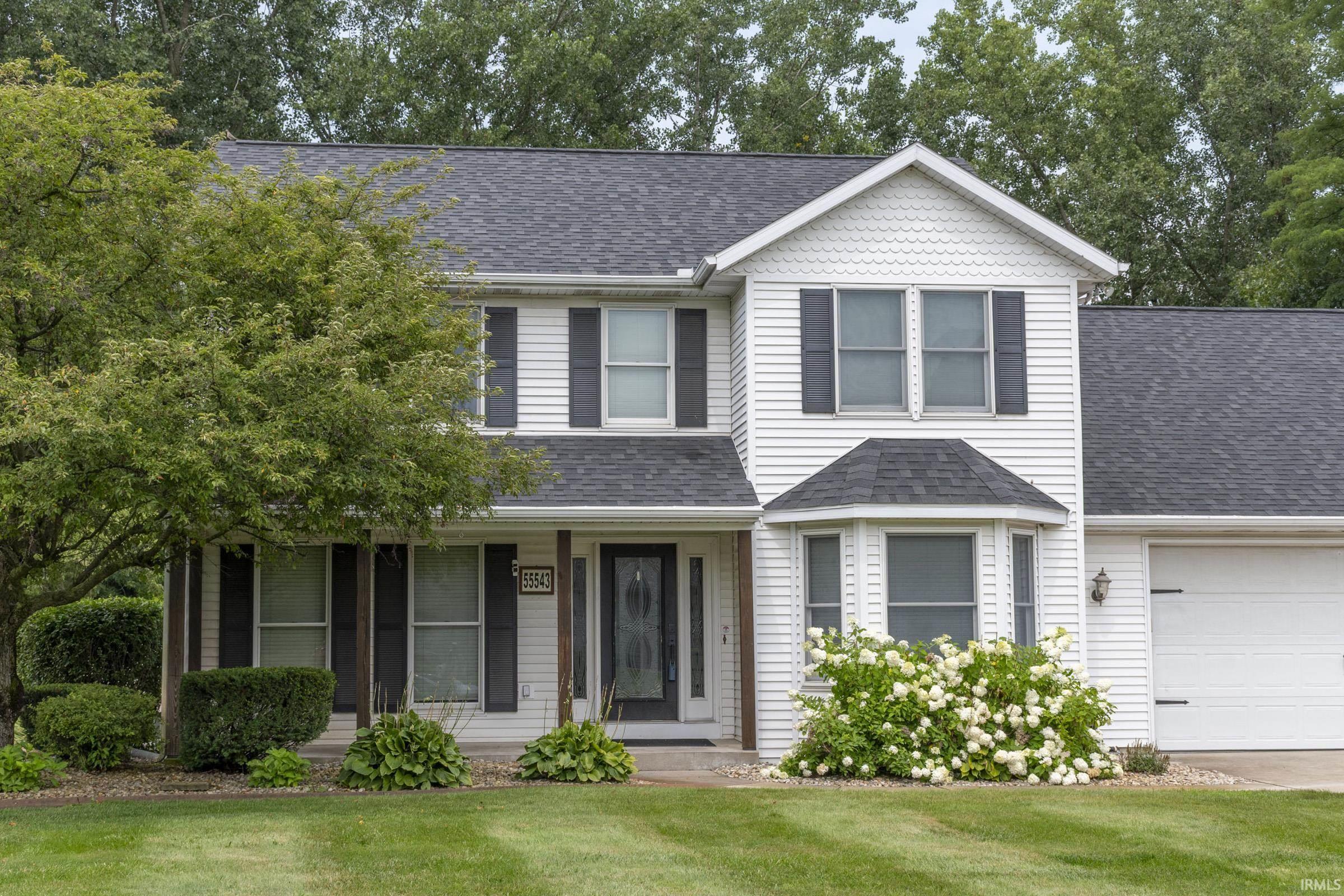 White two-story residence featuring a shingle roof and white siding