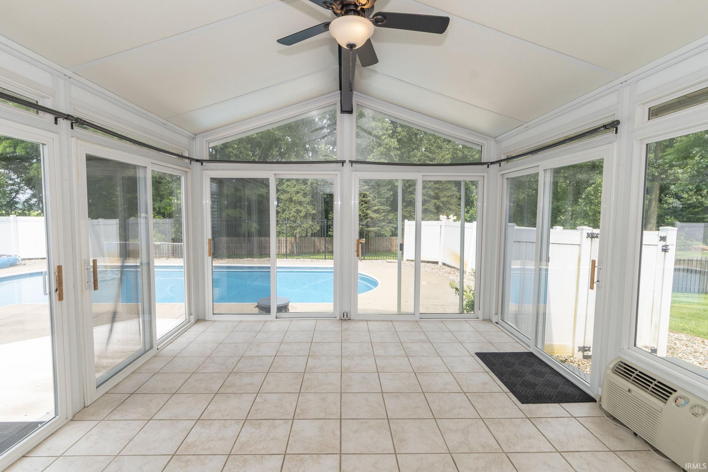 Sunroom with tiled flooring, vaulted ceiling, and overhead ceiling fan