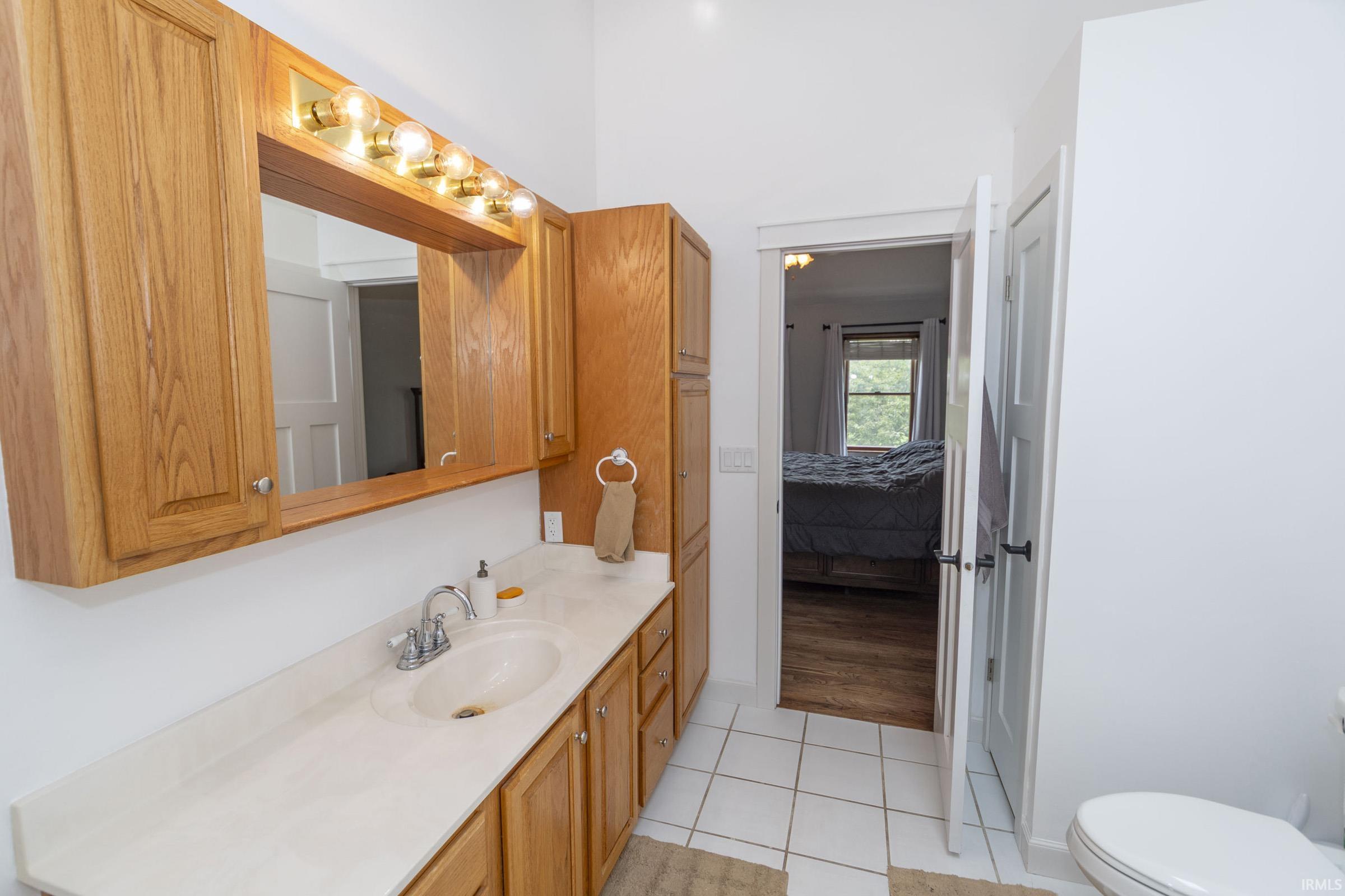 Bathroom featuring a single vanity with wood cabinetry, a white countertop, and a chrome faucet