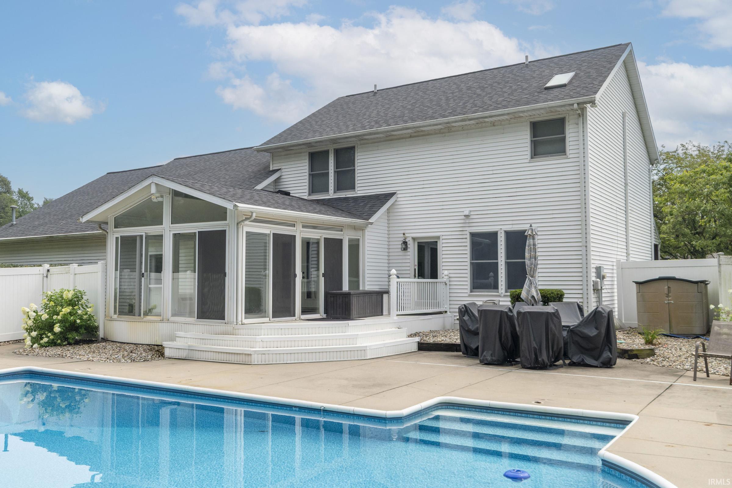 Rear exterior featuring a sunroom, a multi-level deck, and an in-ground swimming pool