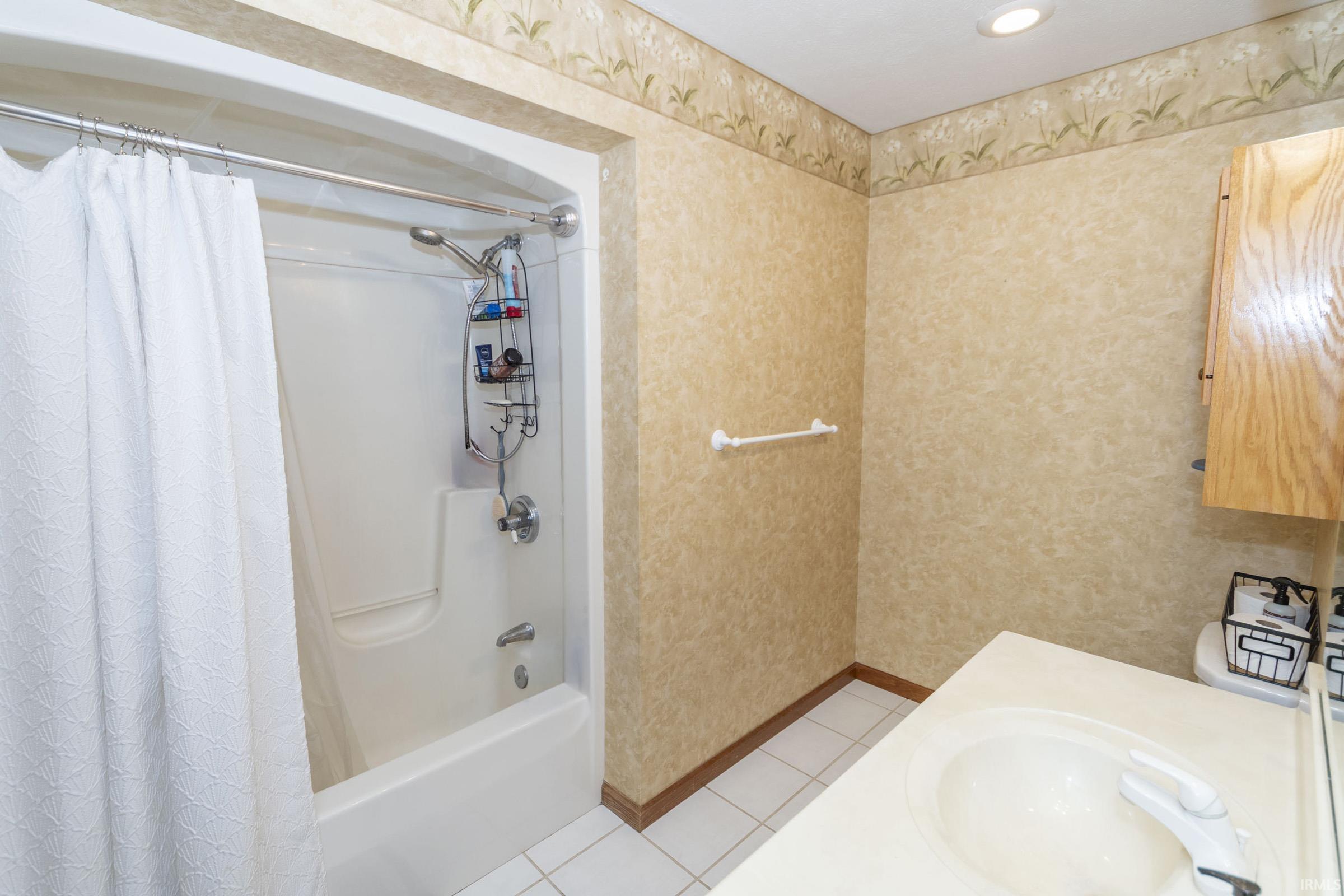 Bathroom featuring a white tub/shower combination with chrome fixtures, a single vanity with an integrated sink, and wood-finish cabinetry