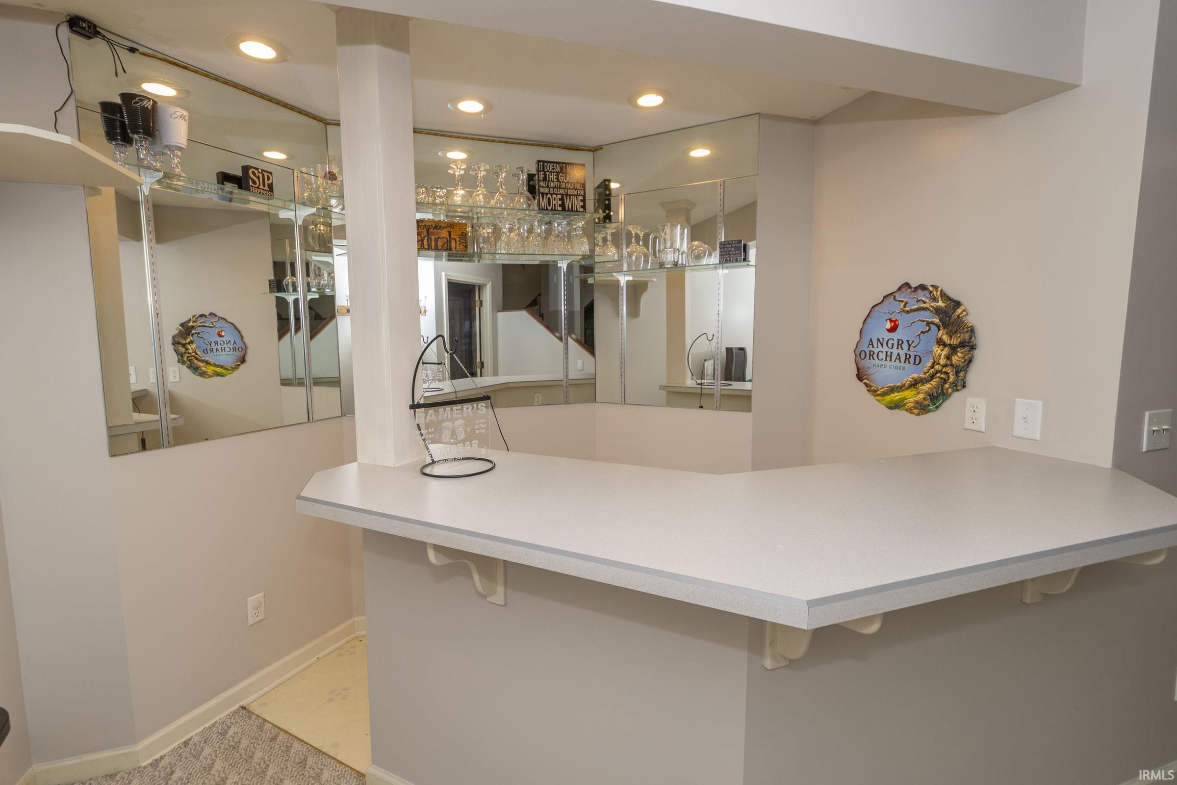 L-shaped bar with a light-toned countertop and mirrored back wall