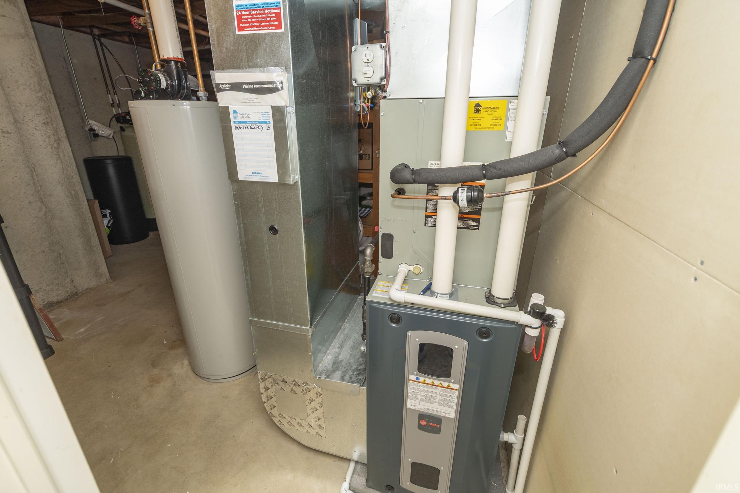 Utility area featuring a water heater, furnace, and exposed ductwork