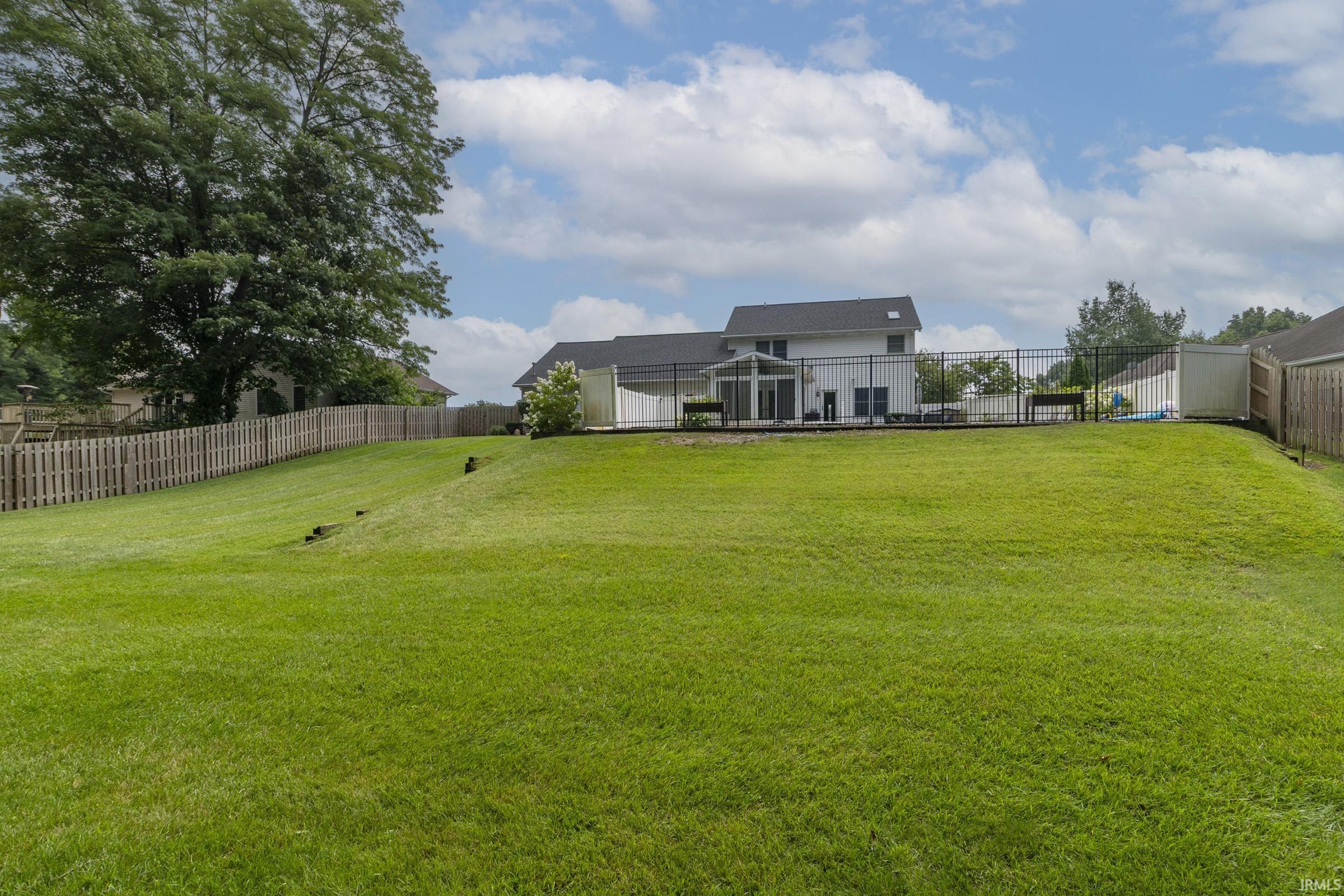 Expansive backyard featuring a lush green lawn and mature trees