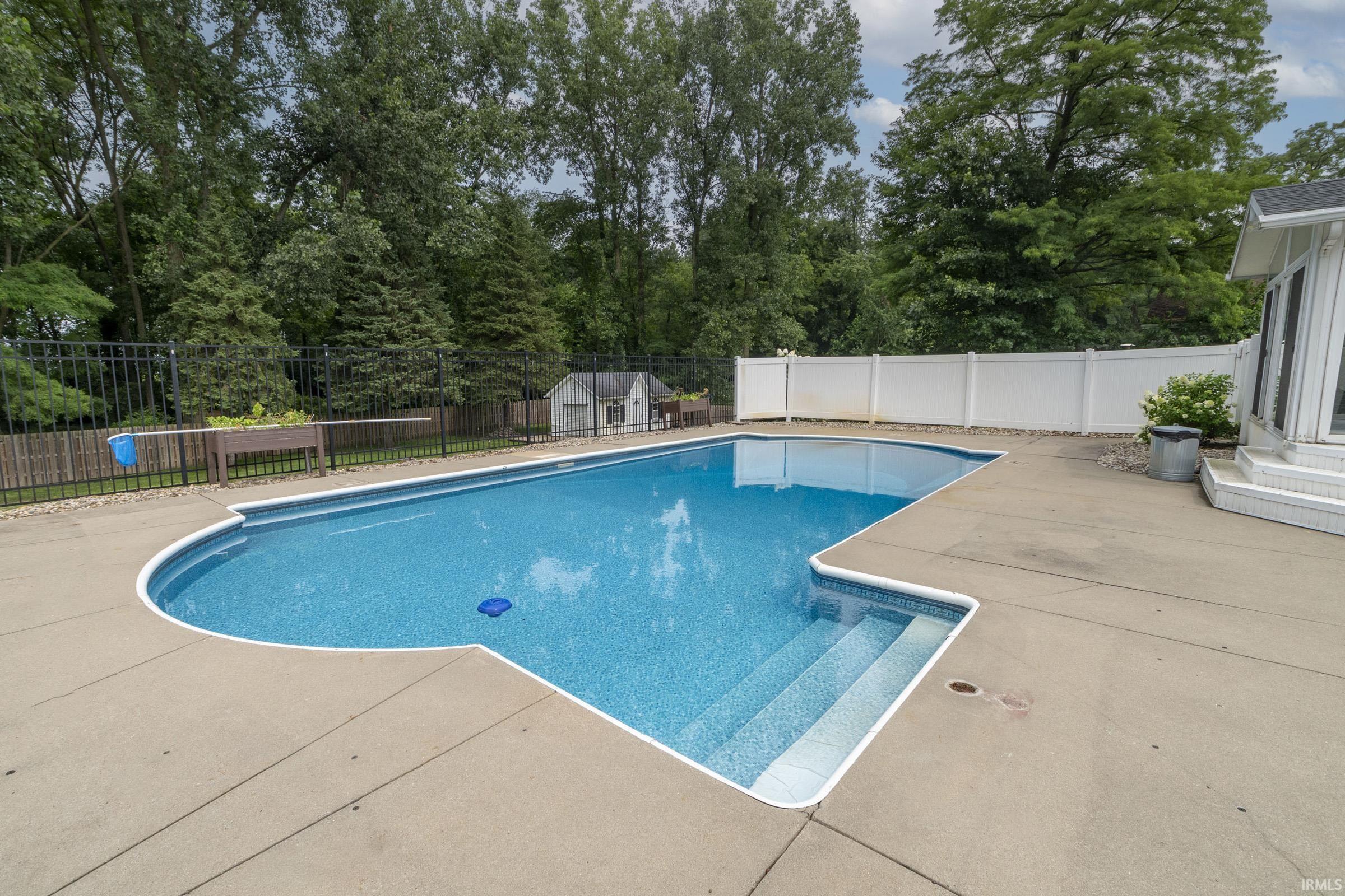 Inviting in-ground swimming pool with integrated steps, surrounded by a concrete patio
