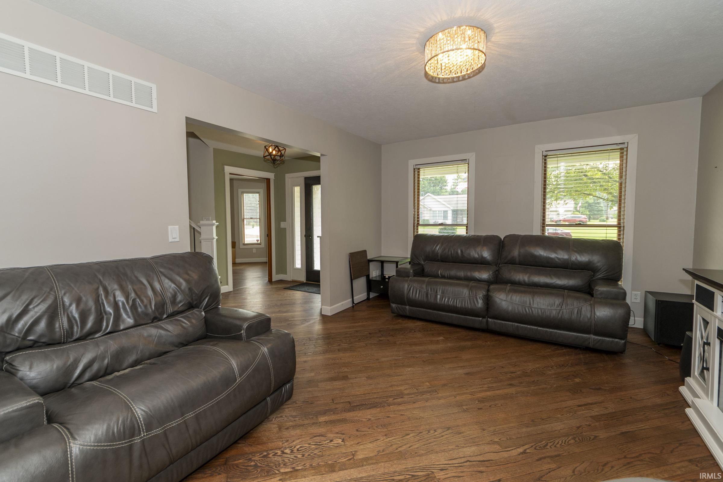 Spacious living area featuring wood-finish flooring, neutral wall tones, and recessed lighting