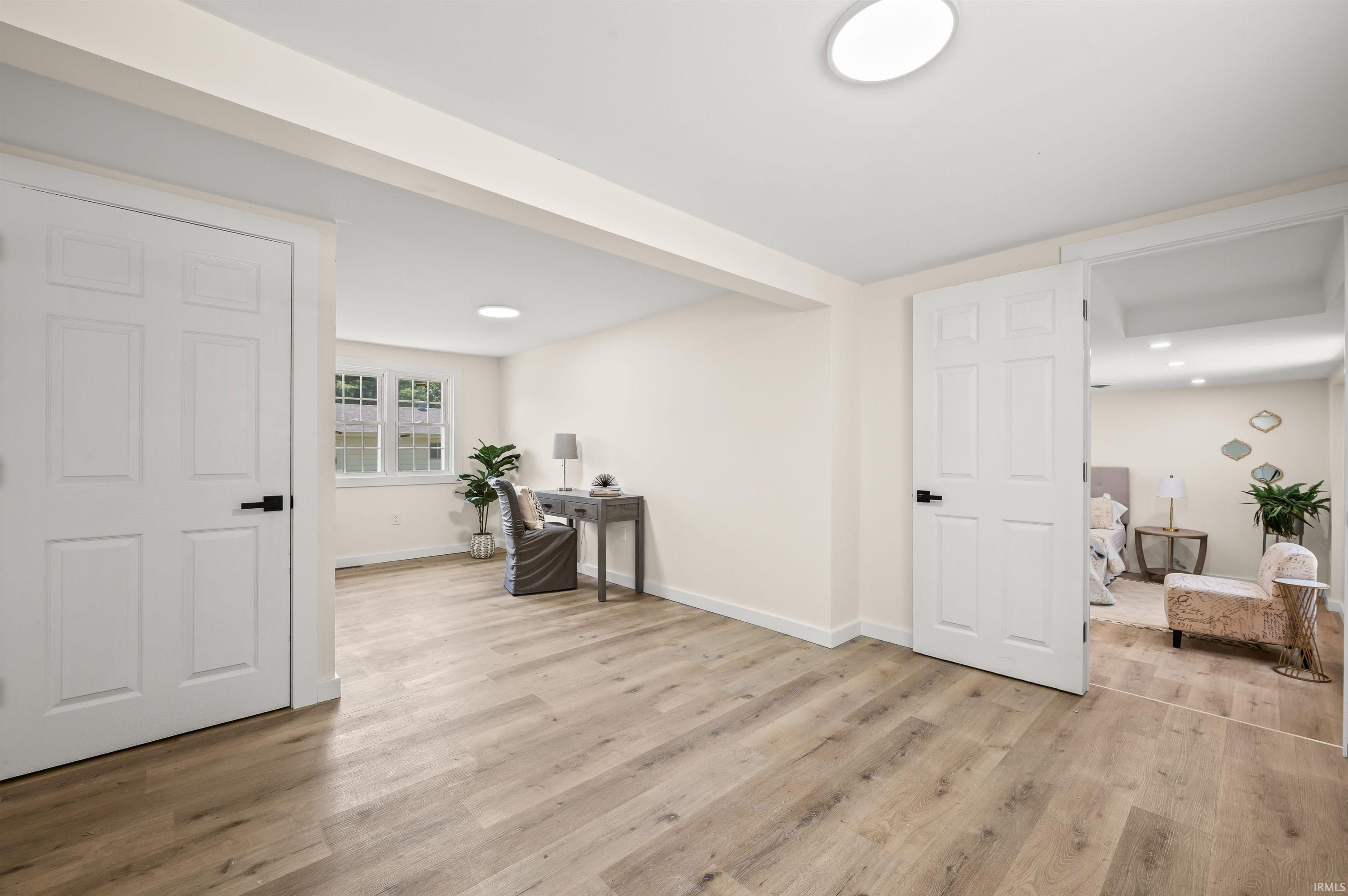 Spacious room featuring wood-finish flooring, white trim, and recessed lighting