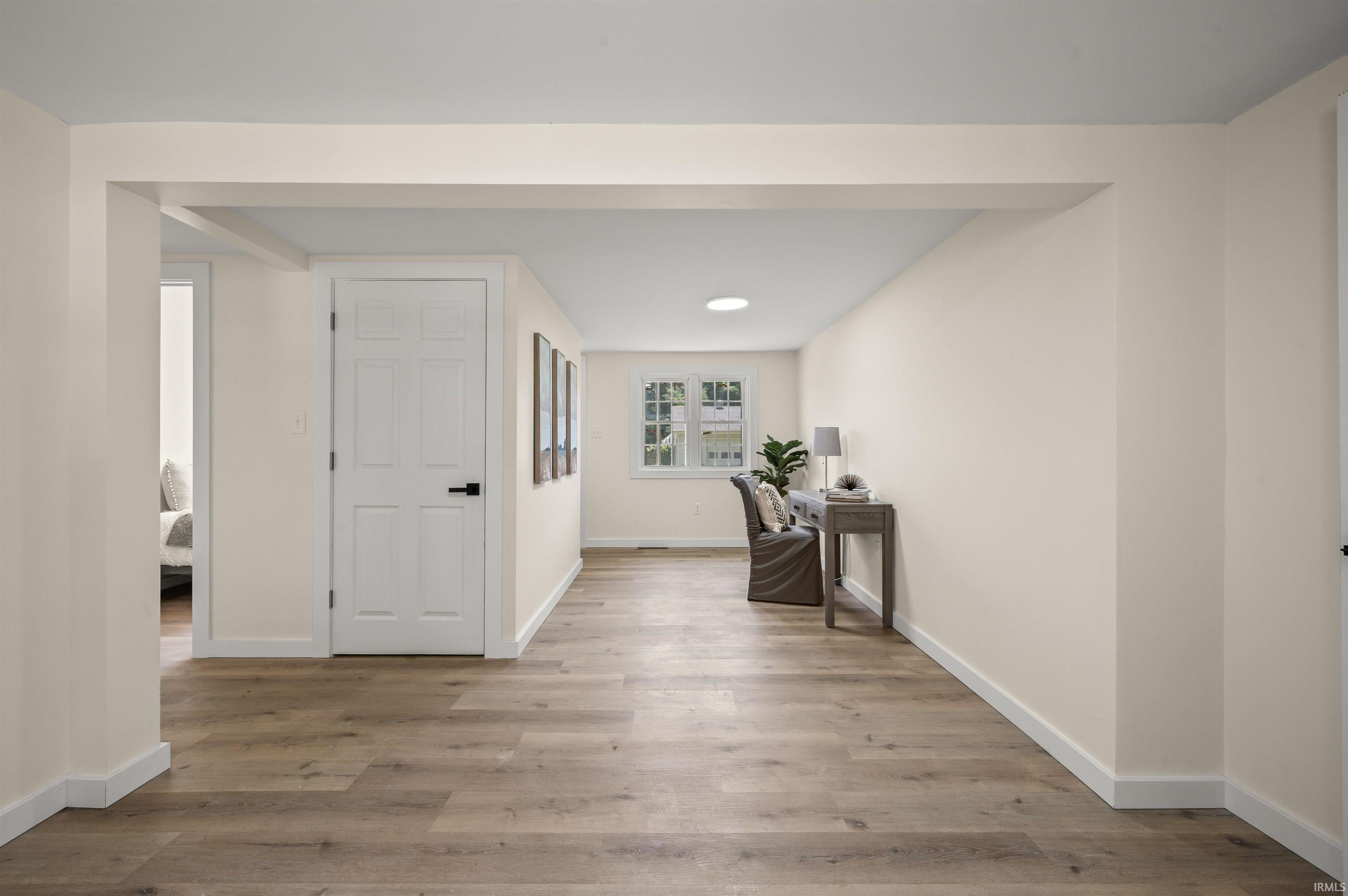 Spacious interior room featuring wood-finish flooring, light neutral wall tones, and white trim