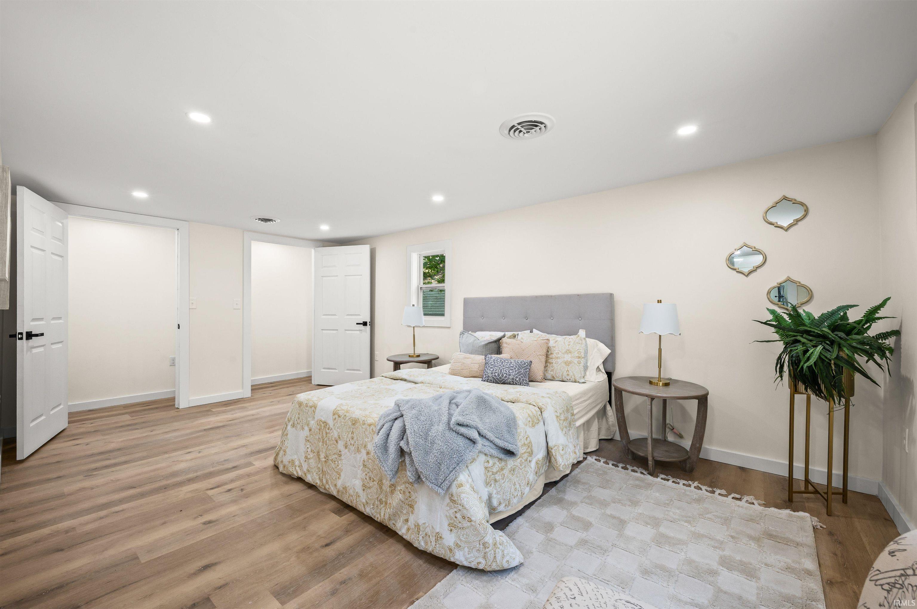 Spacious room featuring wood-finish flooring, recessed lighting, and multiple paneled doors