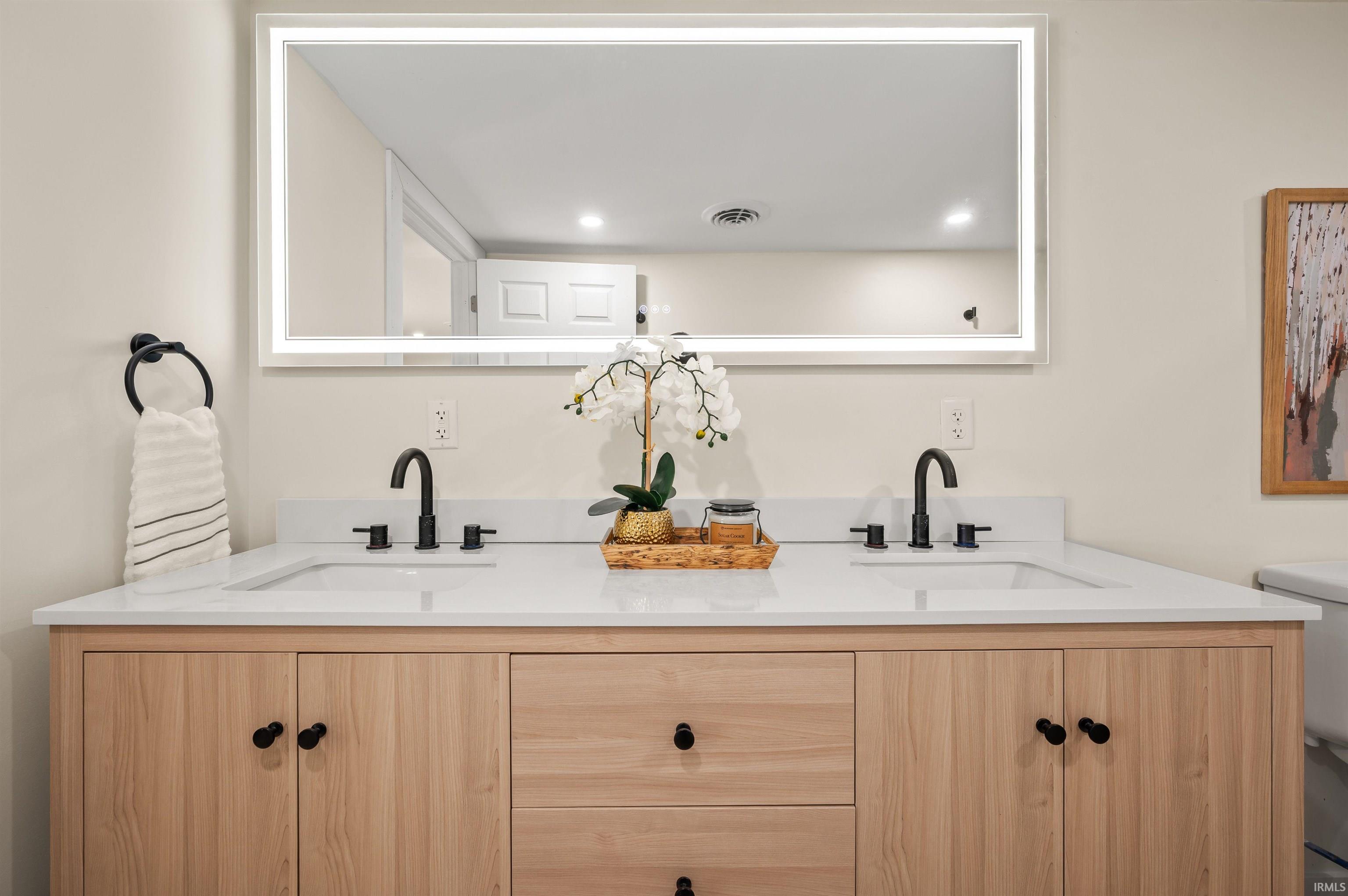 Dual vanity with light wood-finish cabinetry and black hardware