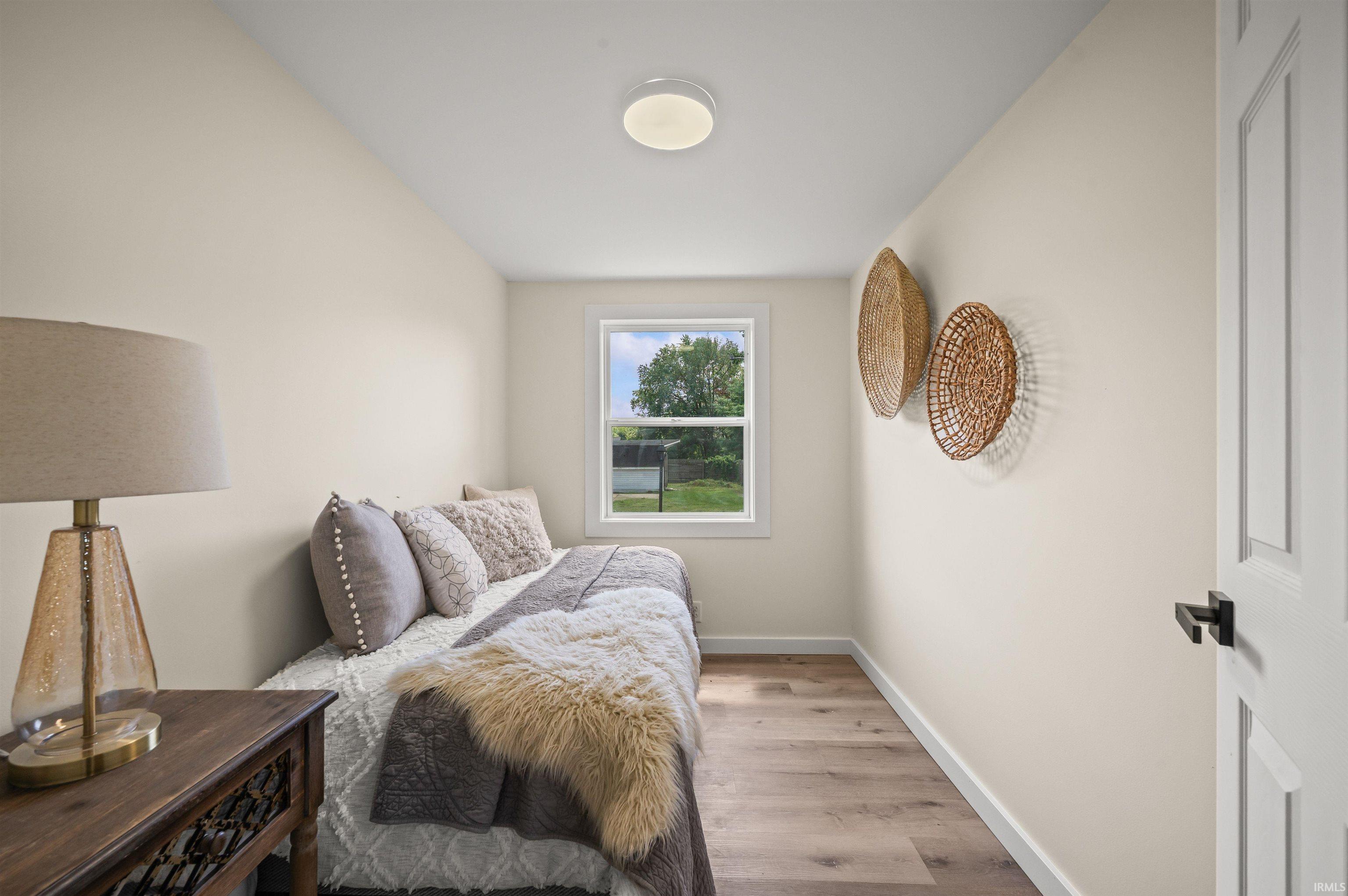 Compact room featuring light-toned walls, wood-finish flooring, and a single window