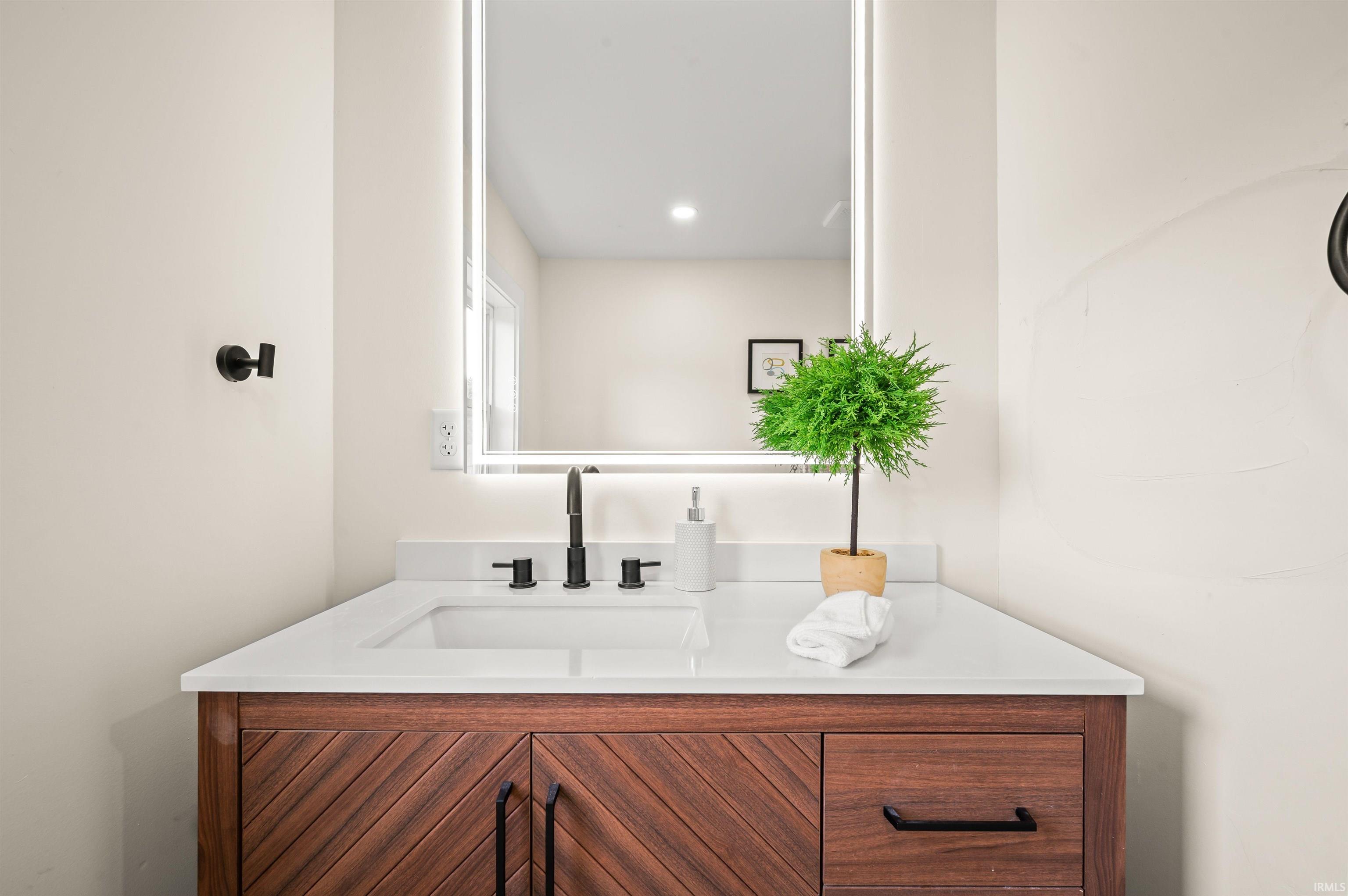 Modern vanity featuring a wood-finish cabinet with chevron detailing and black hardware