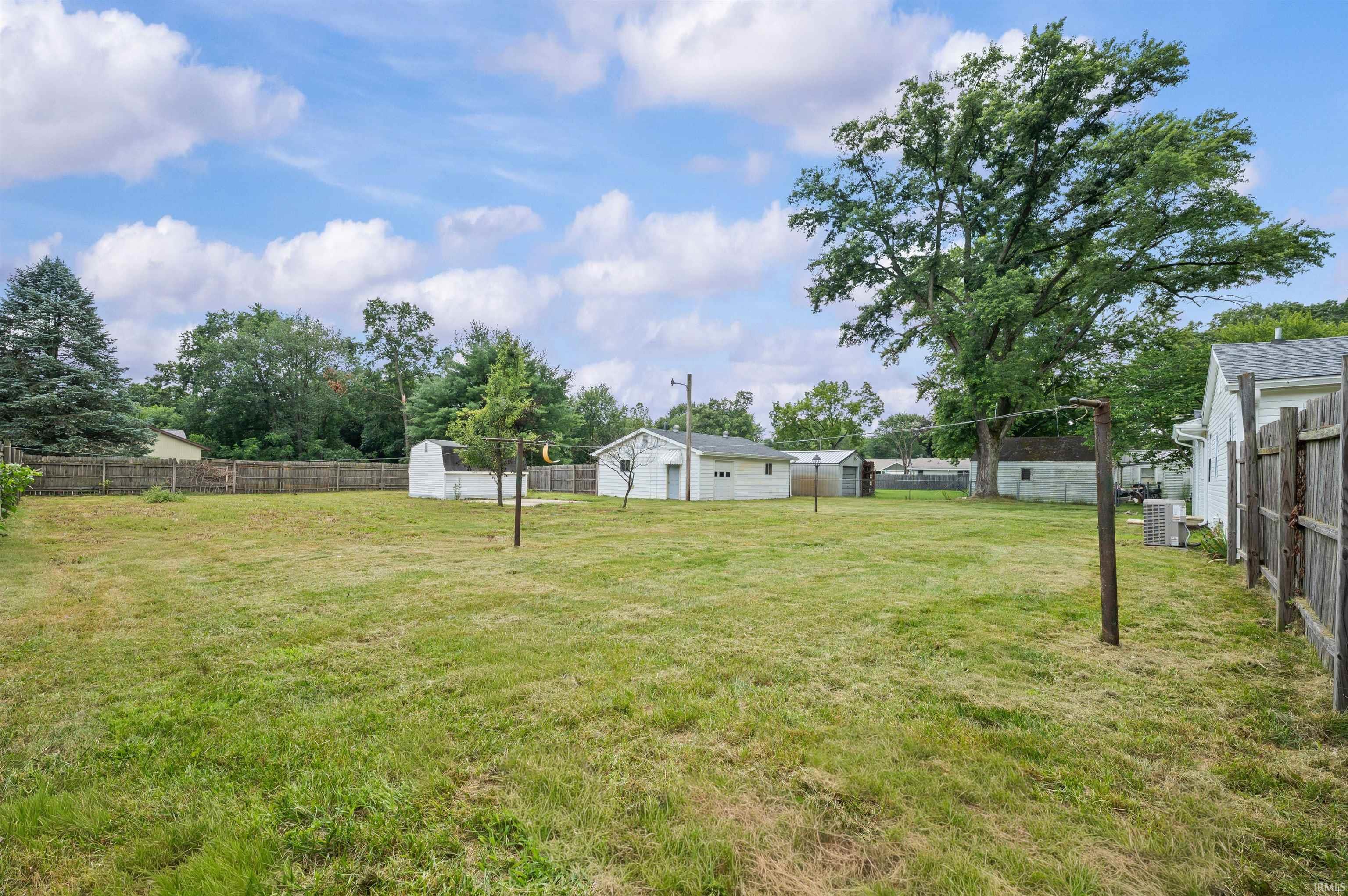 Expansive green space featuring a wood fence perimeter