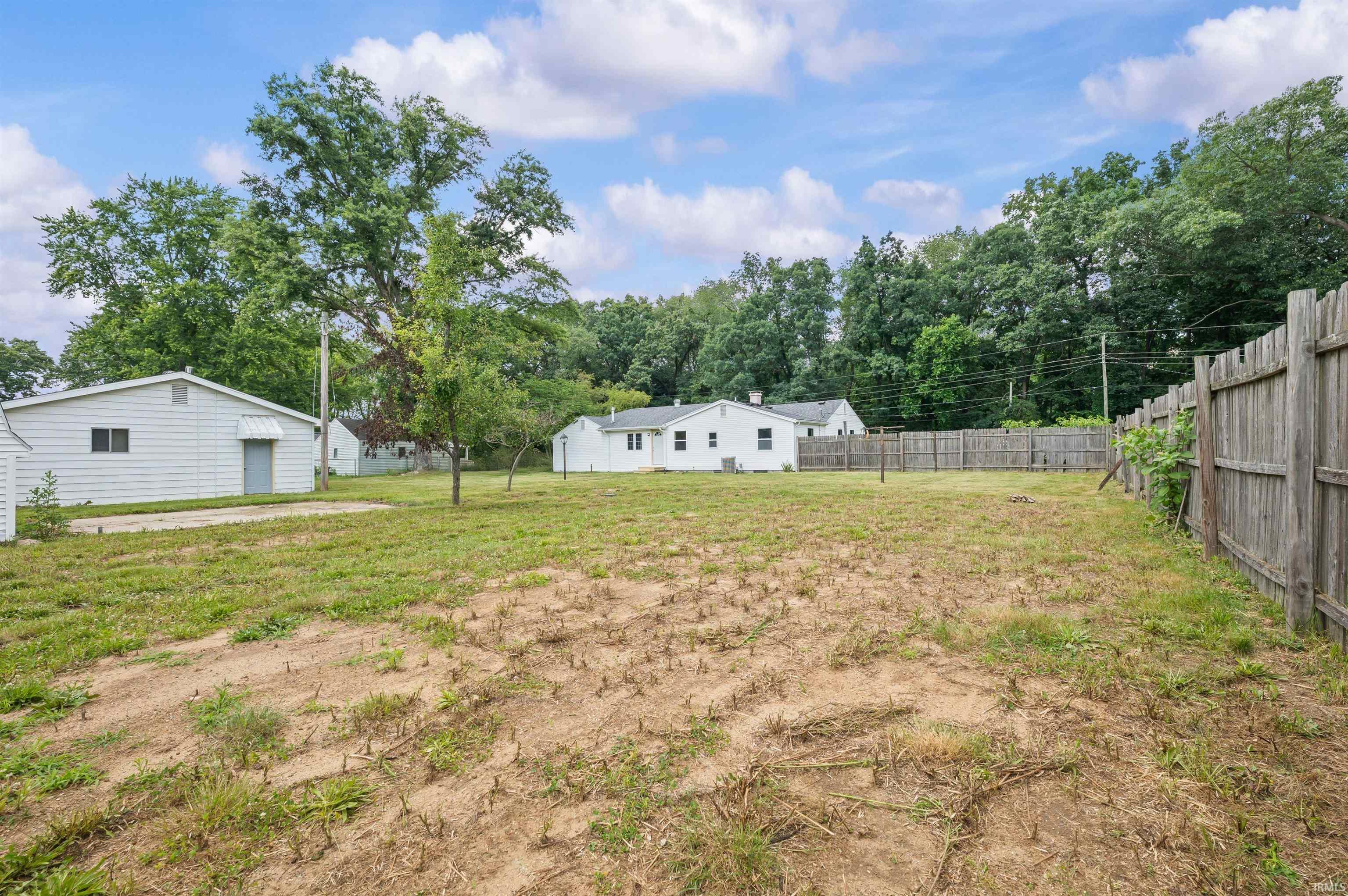Expansive rear yard featuring partial fencing and mature trees