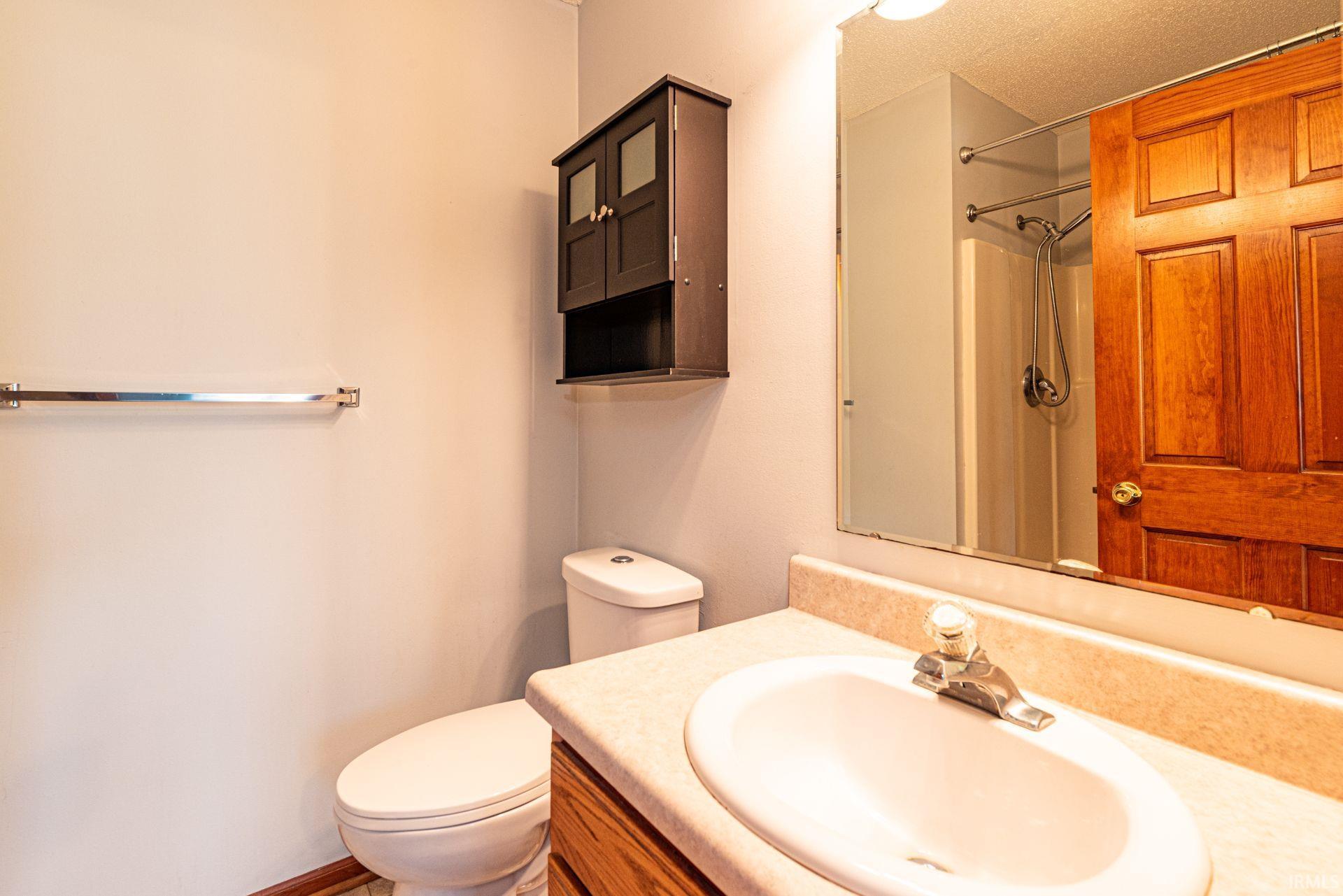 Bathroom featuring a wood-finish vanity with a built-in sink, a wall-mounted mirror, and overhead lighting