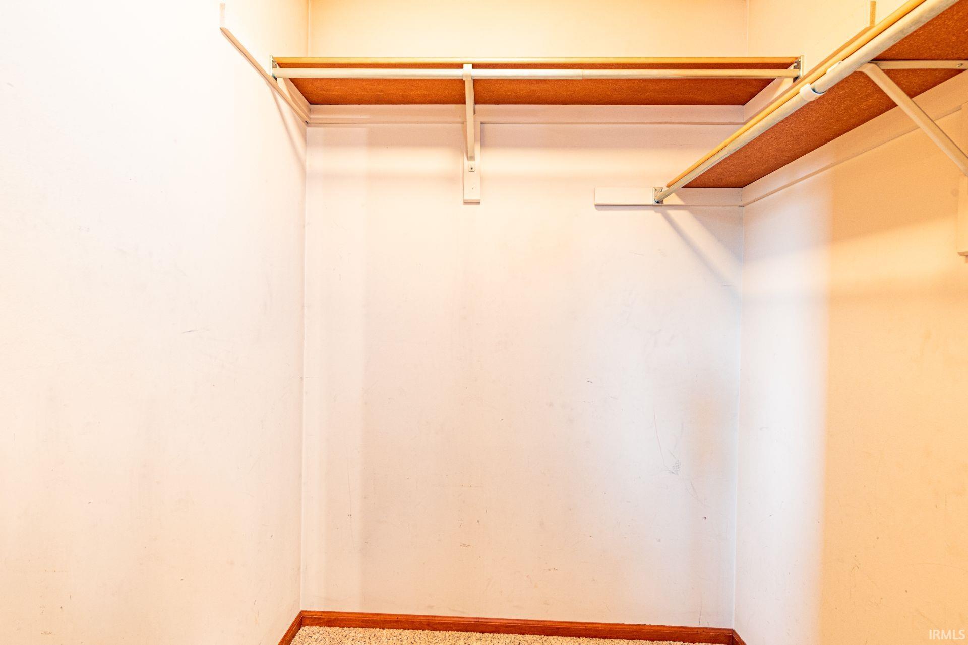 L-shaped closet with built-in shelving, hanging rod, and light-toned walls