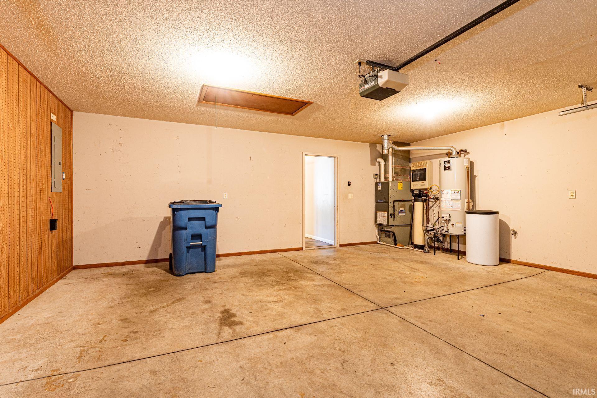 Spacious garage featuring a concrete floor, textured ceiling, and wood-paneled accent wall