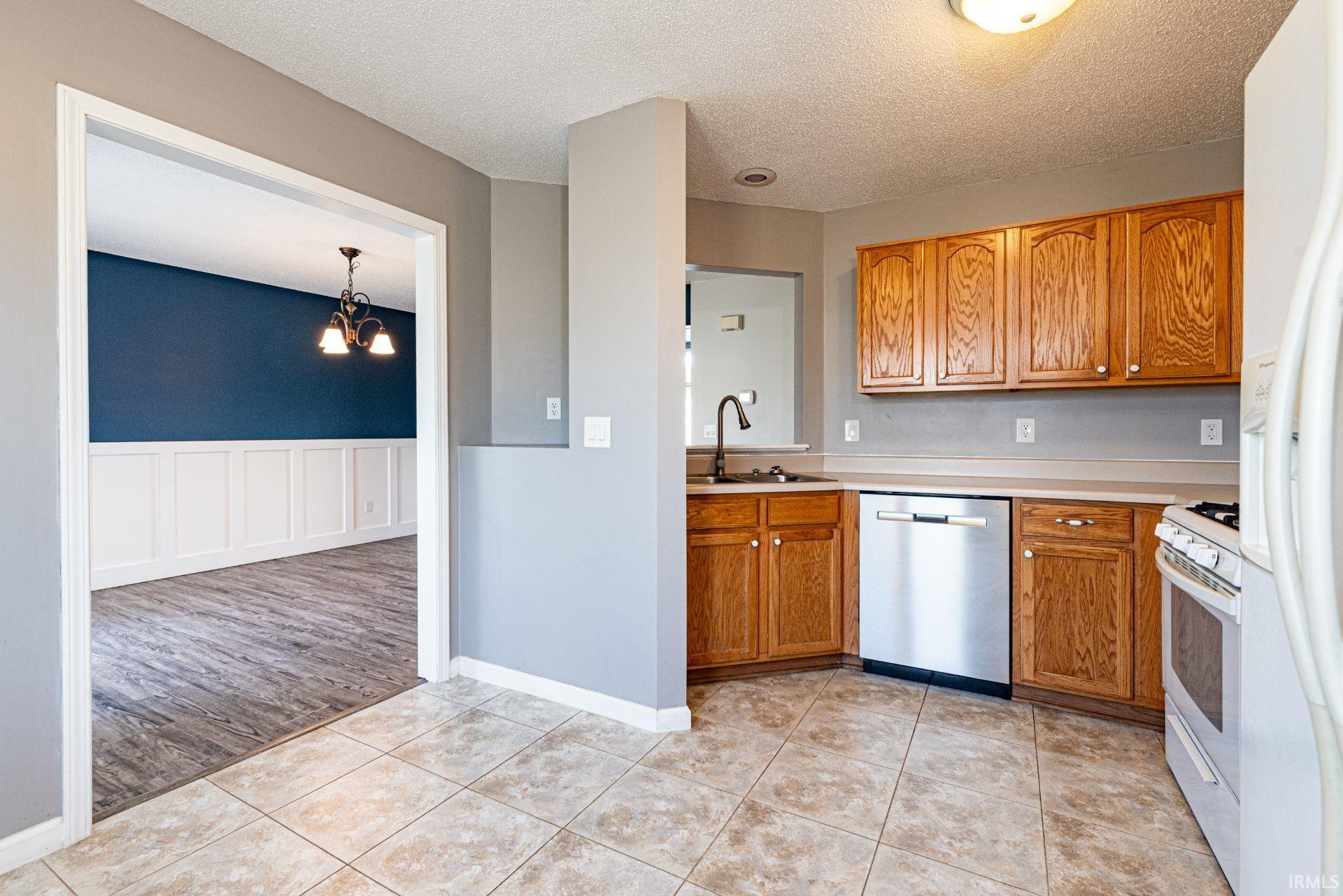 Kitchen featuring wood cabinetry, tile flooring, and stainless steel dishwasher