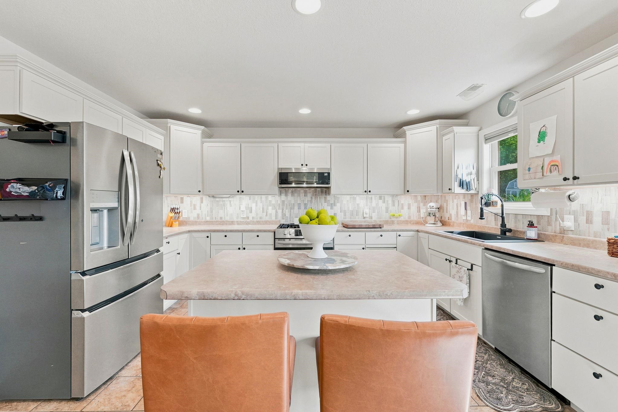 Kitchen featuring white cabinetry, a central island with countertop, stainless steel appliances, a tile backsplash, and recessed lighting with extra seating