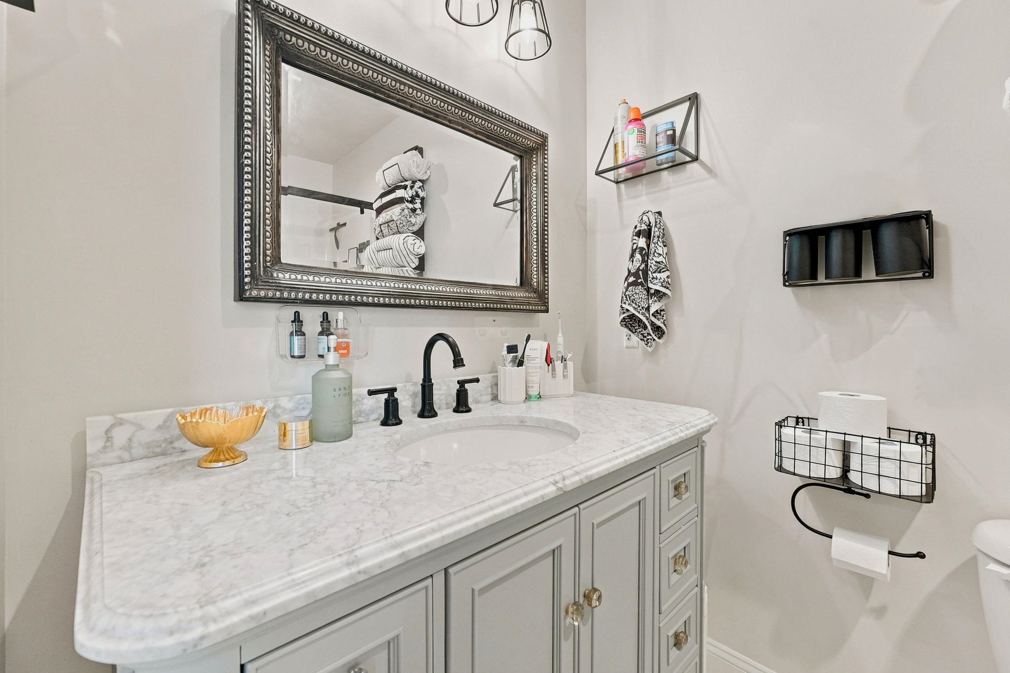 Bathroom vanity featuring a marble countertop, undermount sink, and matte black faucet