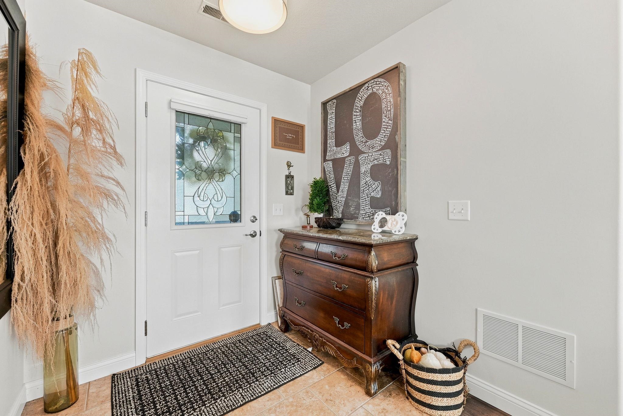 Entryway featuring a white door with a decorative glass insert, tiled flooring, and a flush-mount ceiling light fixture