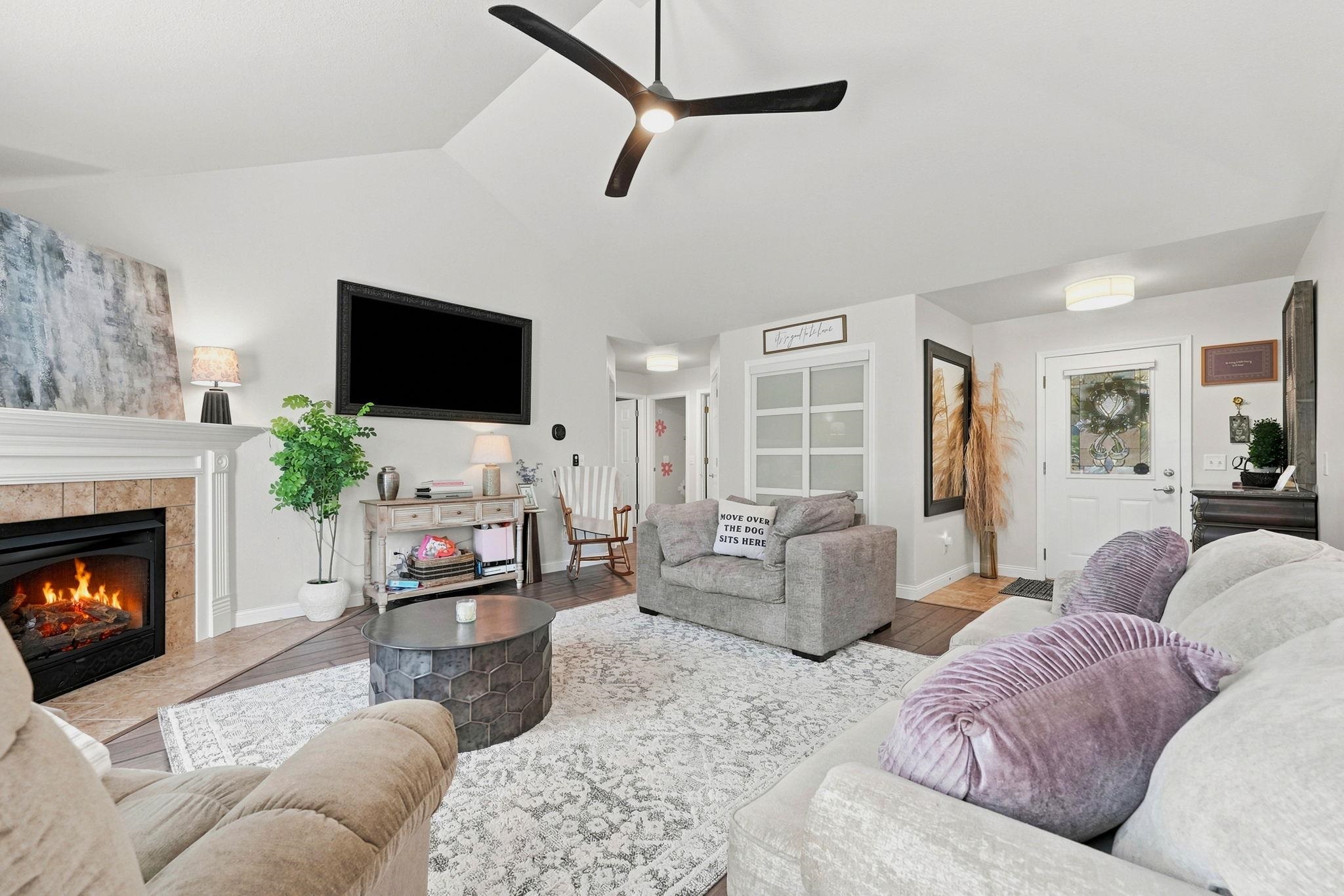 Living space featuring a vaulted ceiling and a ceiling fan and fireplace