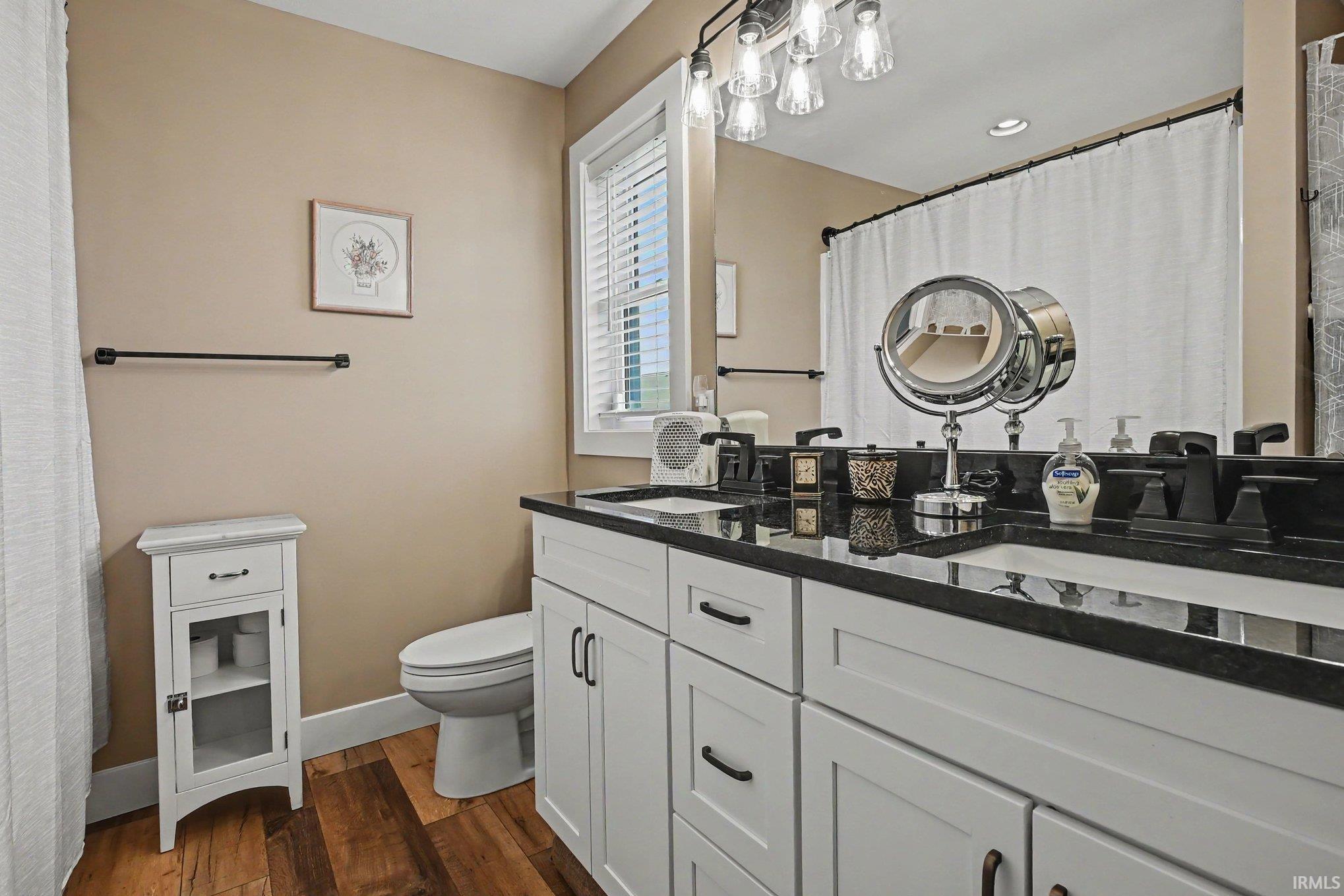 Double vanity featuring white cabinetry, black countertops, and two undermount sinks