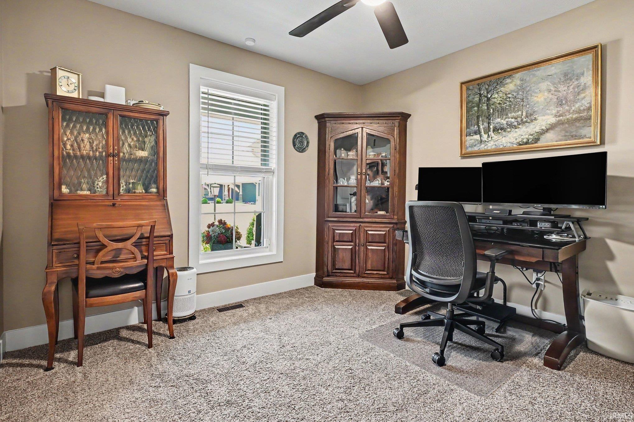 Carpeted room featuring a ceiling fan with integrated lighting, a single window with blinds, and neutral-toned walls