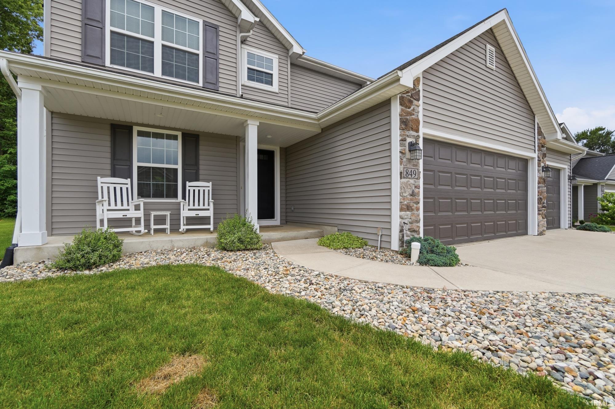 Exterior residence featuring gray siding, a stone facade accent, and a covered front porch with white columns