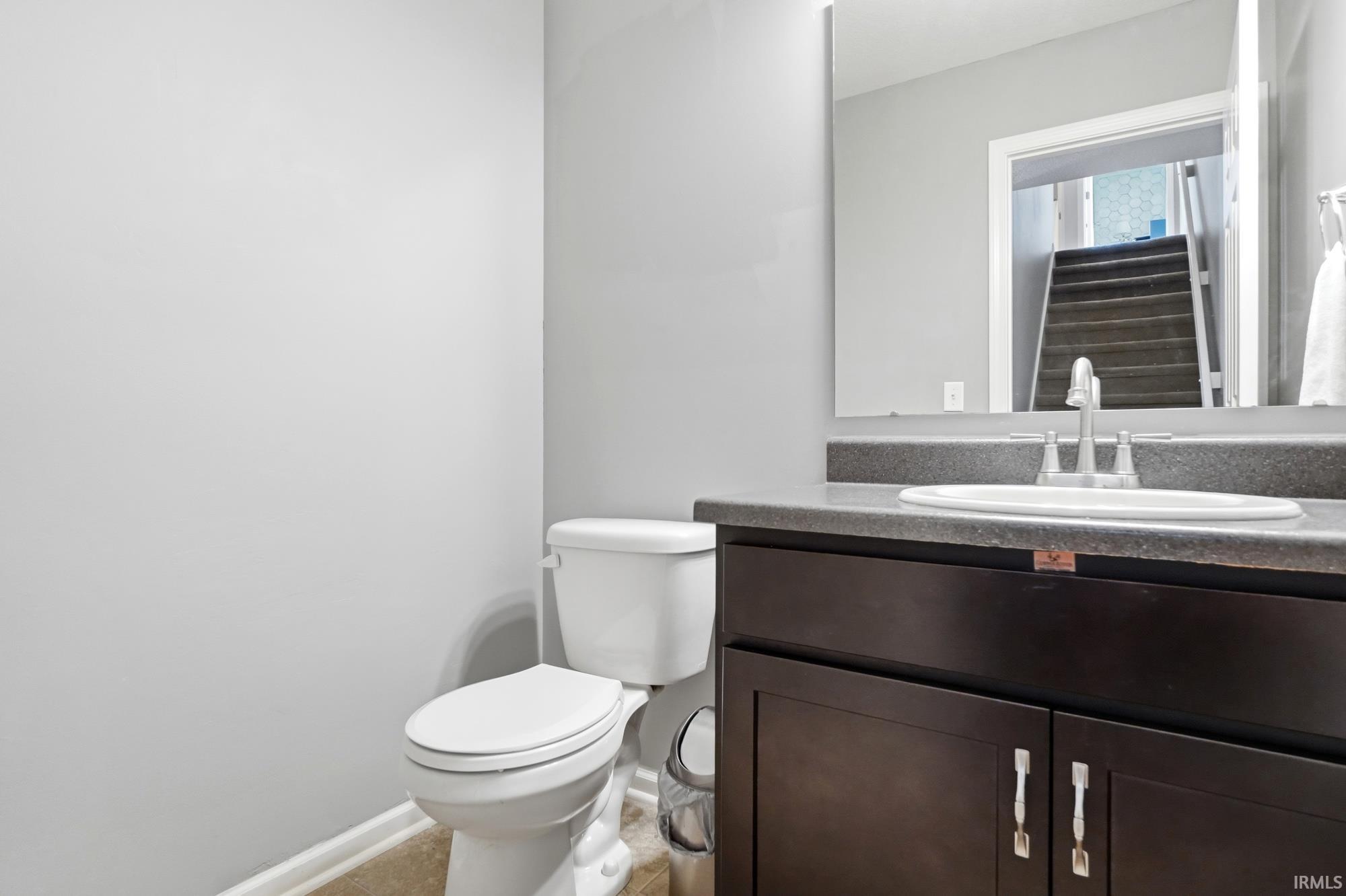Bathroom featuring a dark wood-finish vanity with a built-in sink, gray countertop, and a wall-mounted mirror