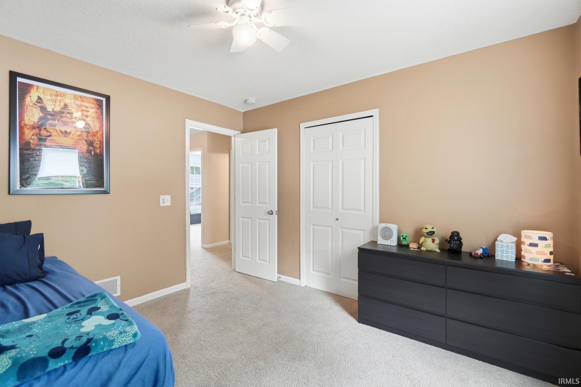 Neutral tone walls, ceiling fan, carpet flooring, a bifold door closet, and an interior door