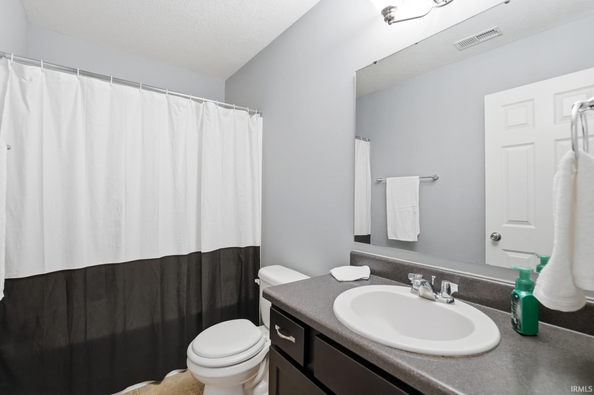 Bathroom featuring a vanity with an integrated sink, dark countertop, and chrome faucet
