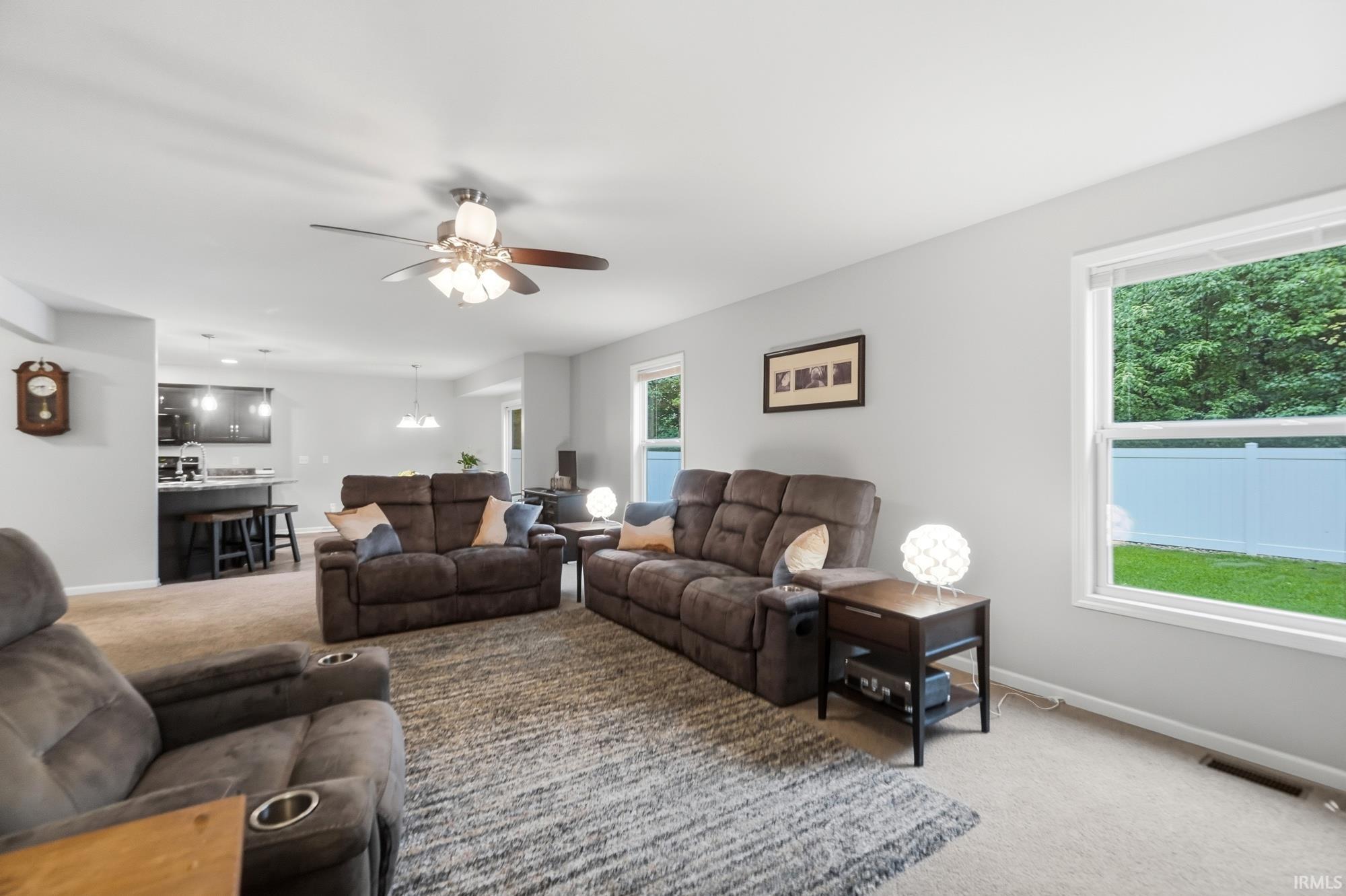 Recessed lighting, ceiling fan with light fixture, carpeted flooring, white trim, and a kitchen pass-through with a breakfast bar