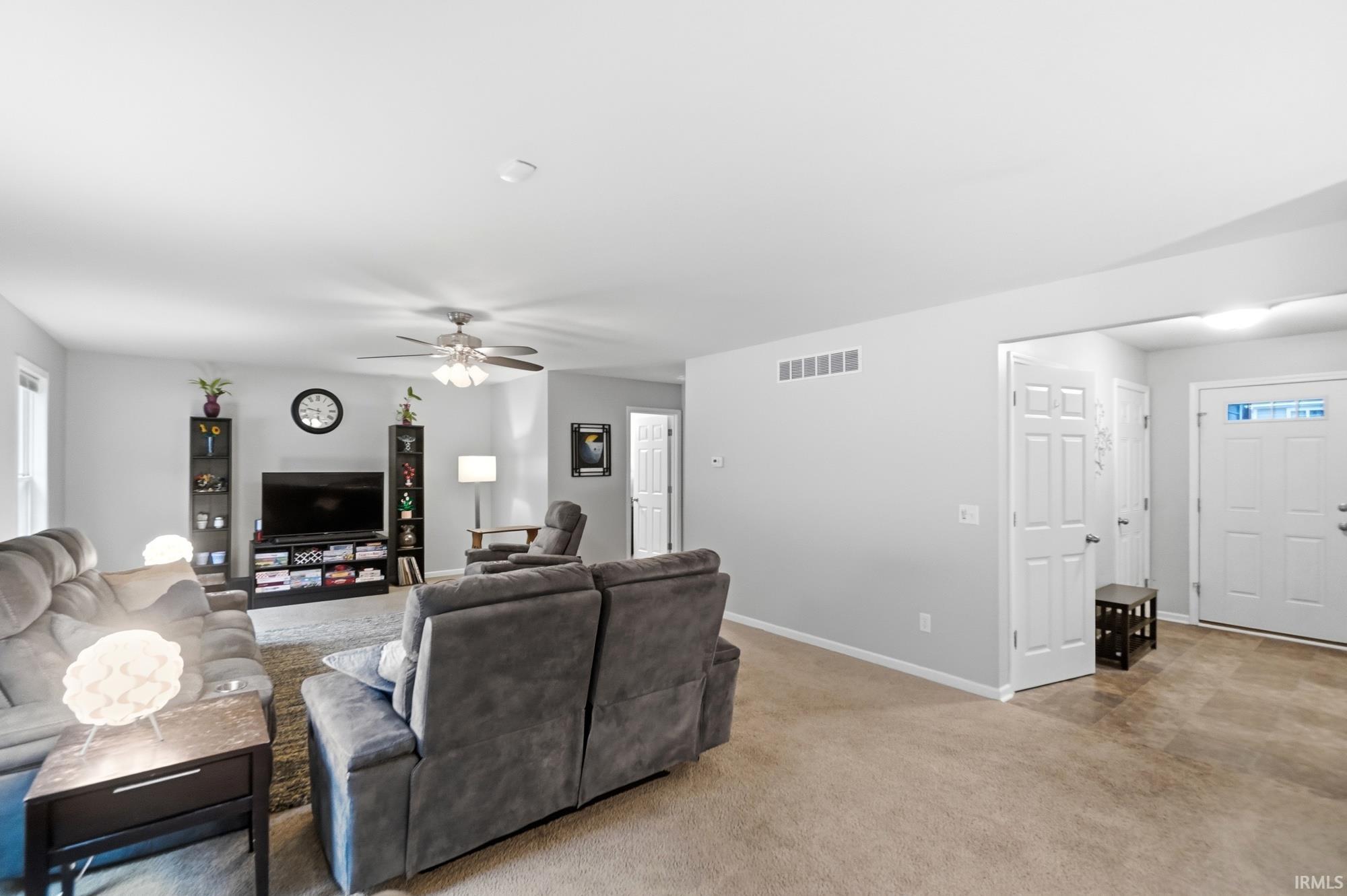 Expansive living area with neutral wall tones and a ceiling fan
