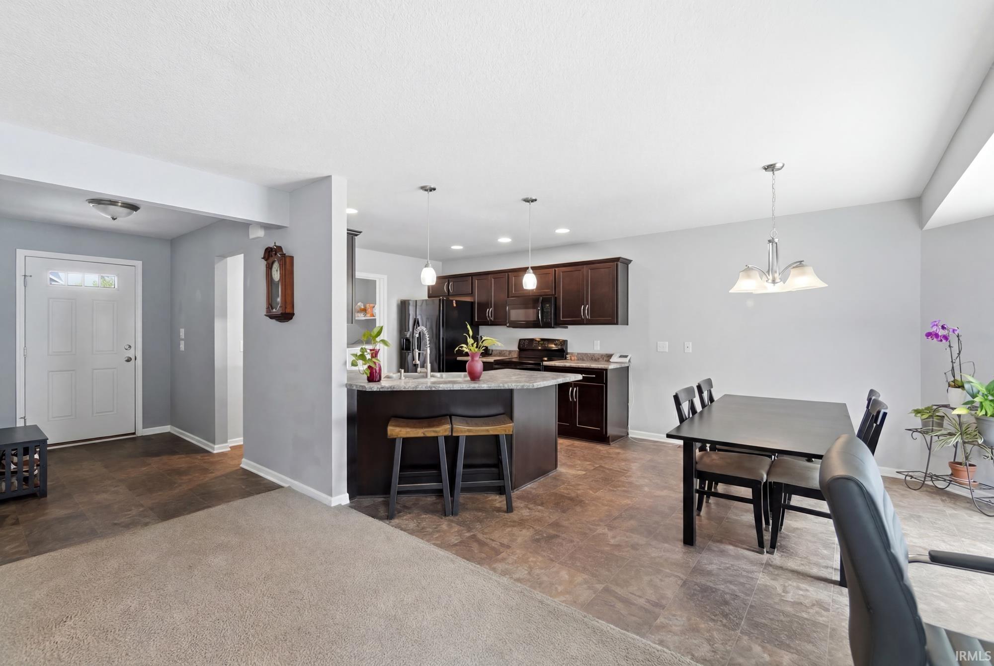 Contemporary kitchen featuring dark wood cabinetry, stainless steel appliances, and a granite-style island with seating