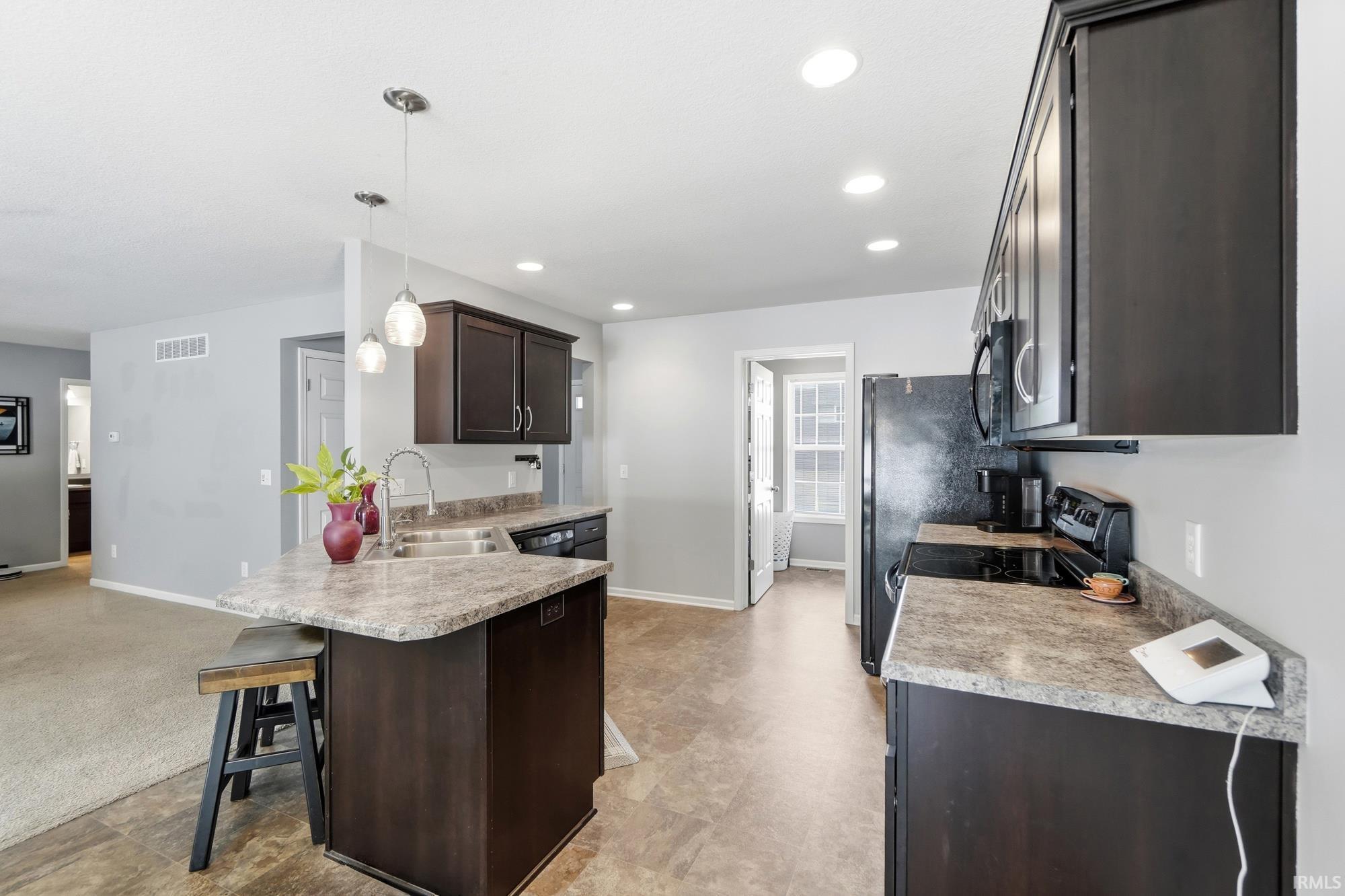 Kitchen featuring dark wood cabinetry, light-toned countertops, and recessed lighting