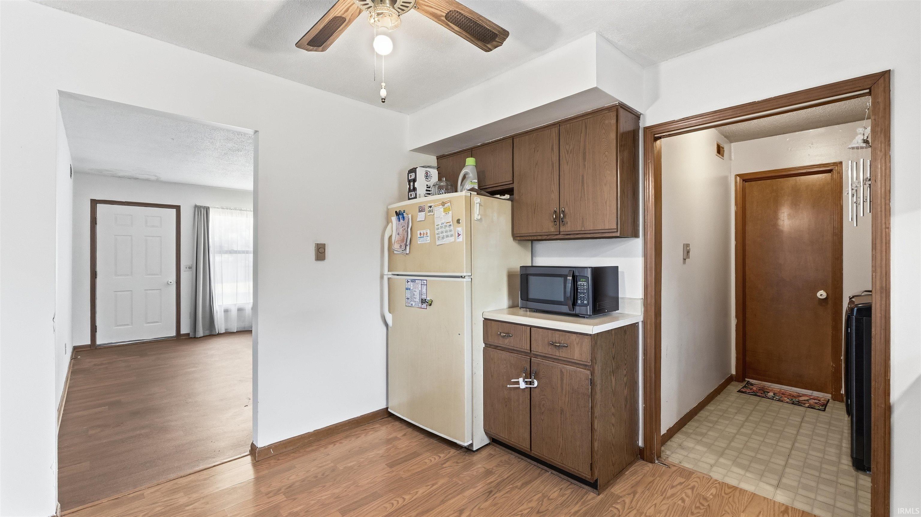 Kitchen featuring wood-finish flooring, wood cabinetry, and a ceiling fan with light fixture
