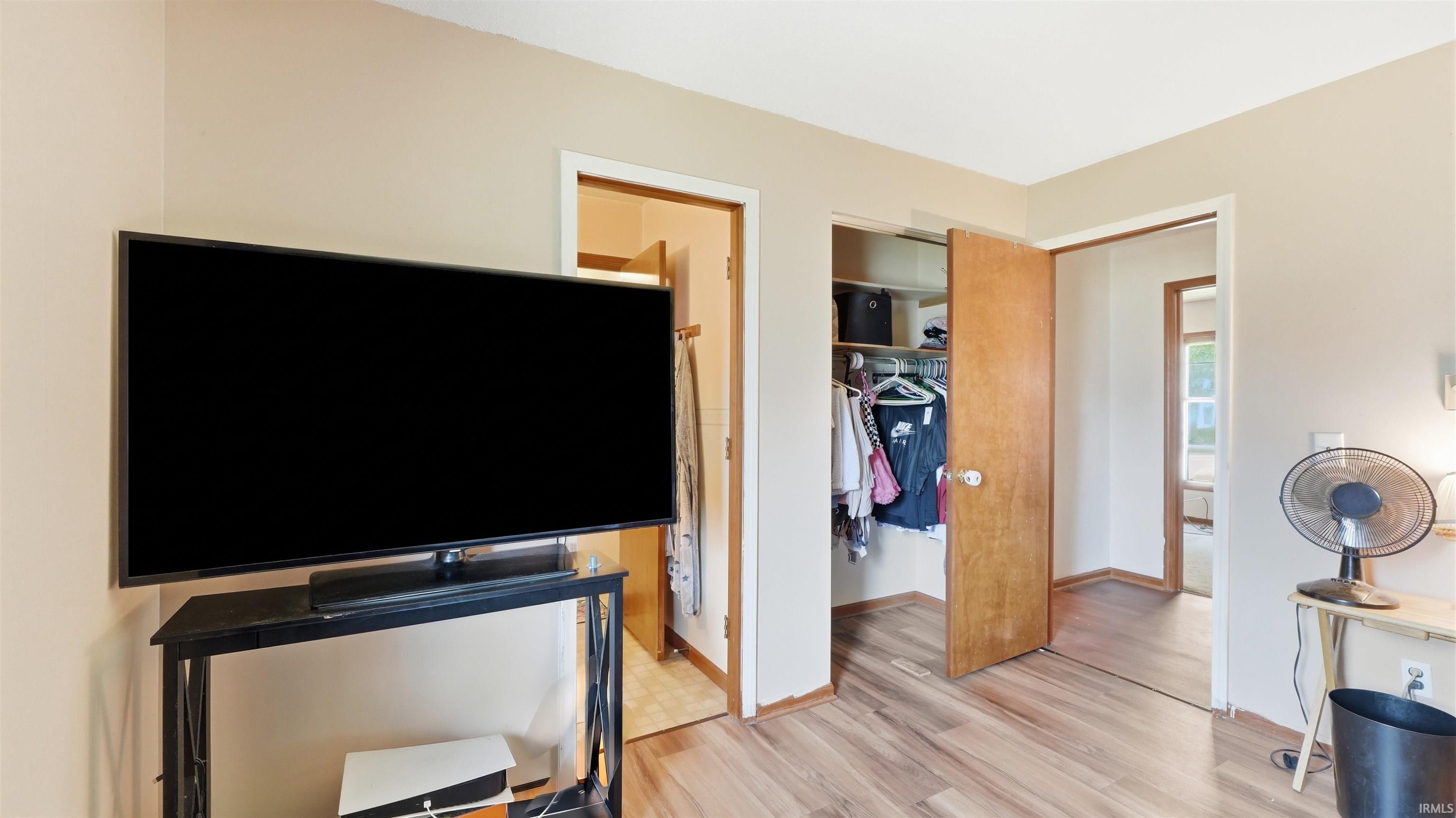 Interior room featuring wood-finish flooring, two doorways with wood-panel doors, and neutral wall paint