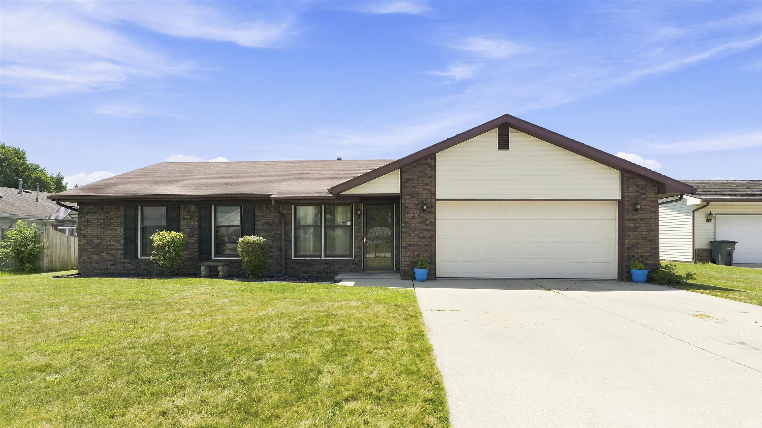 Ranch-style residence featuring brick and siding exterior, a two-car garage, and an asphalt driveway