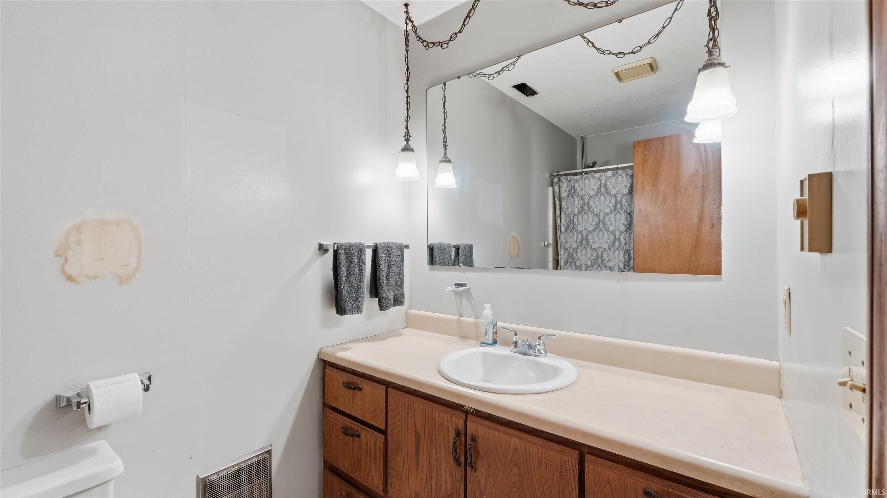Vanity featuring a white basin sink, laminate countertop, and wood-finish cabinetry