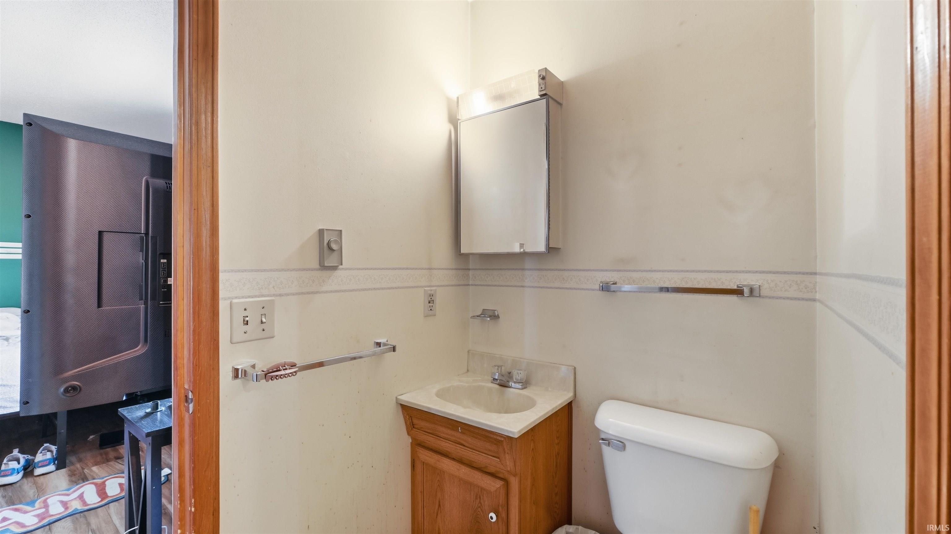 Bathroom featuring a wood vanity with integrated sink, white toilet, and mirrored medicine cabinet