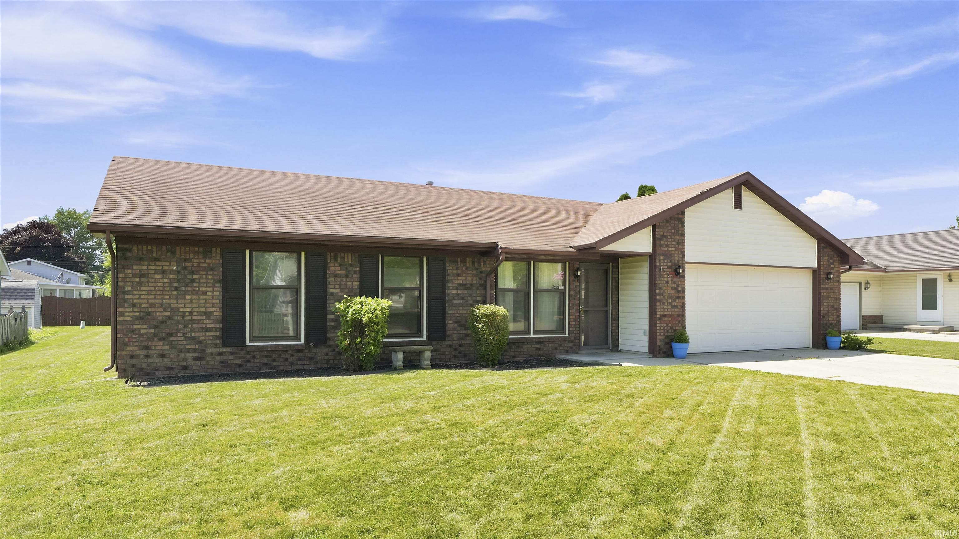Ranch-style residence featuring a brick facade, attached two-car garage, and a concrete driveway