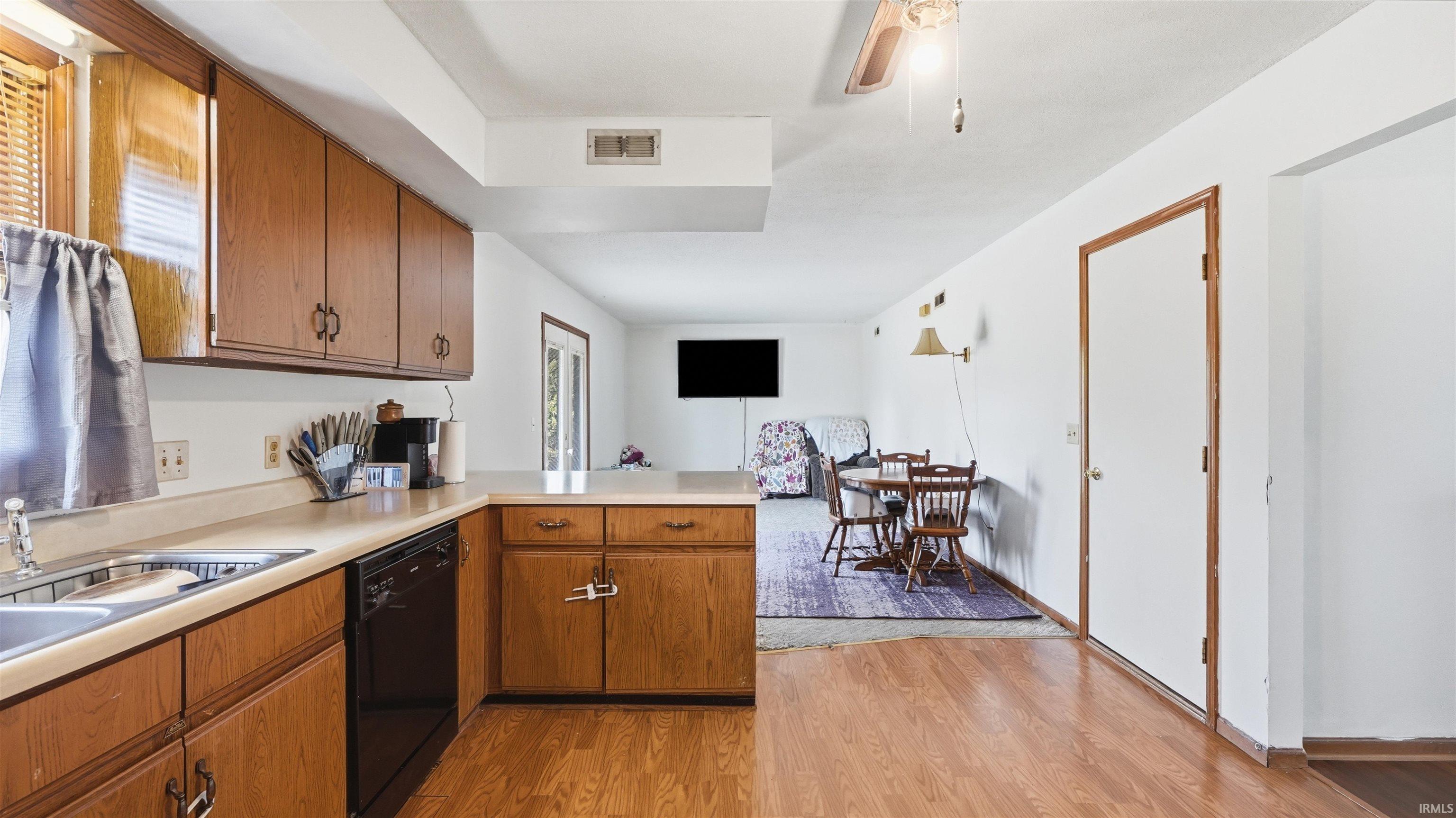Kitchen featuring wood-finish cabinetry, light-toned countertops, and a double basin sink