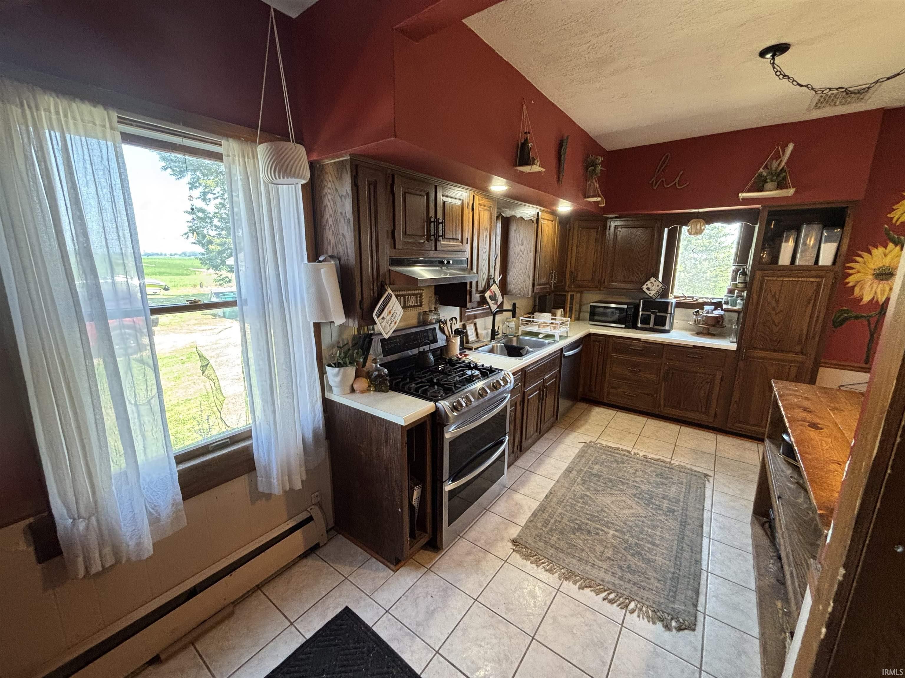 Kitchen featuring a gas range, stainless steel dishwasher, double-basin sink, and ample wood cabinetry