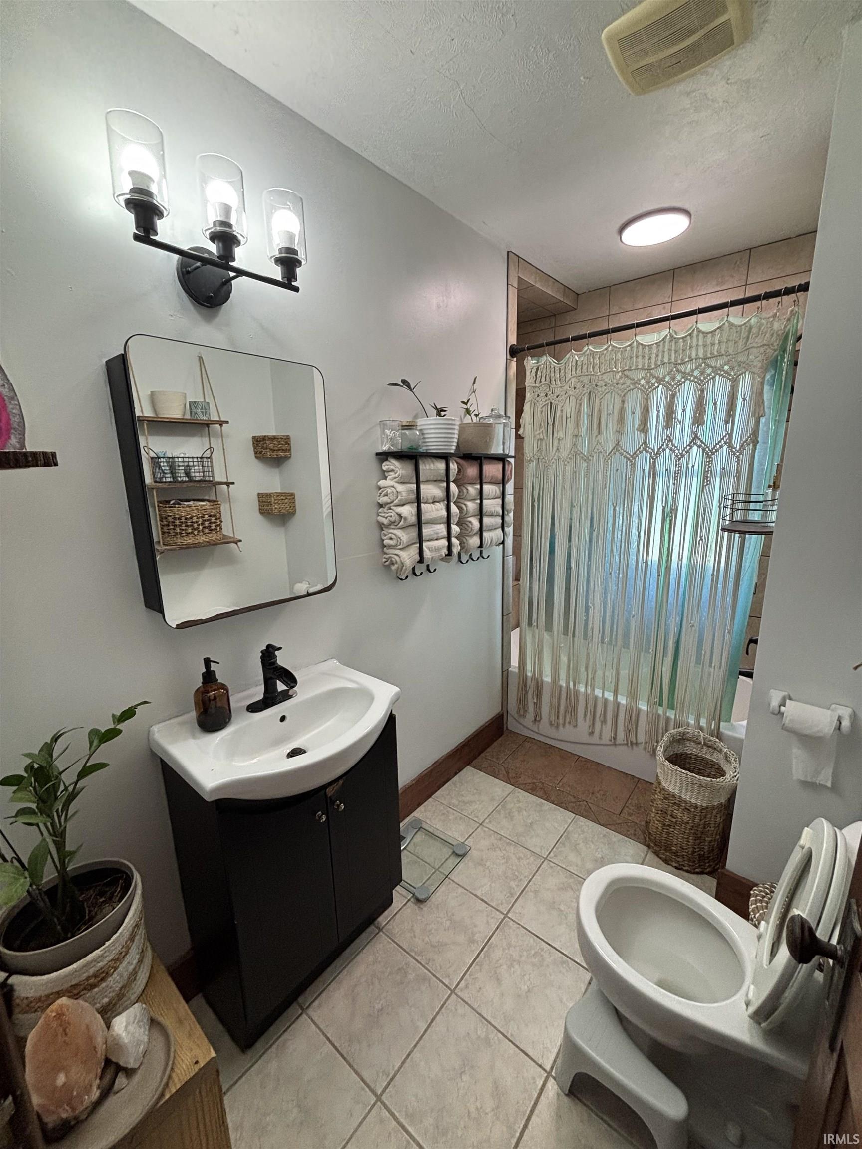 Bathroom featuring a vanity with a white basin sink, dark cabinetry, and a black faucet